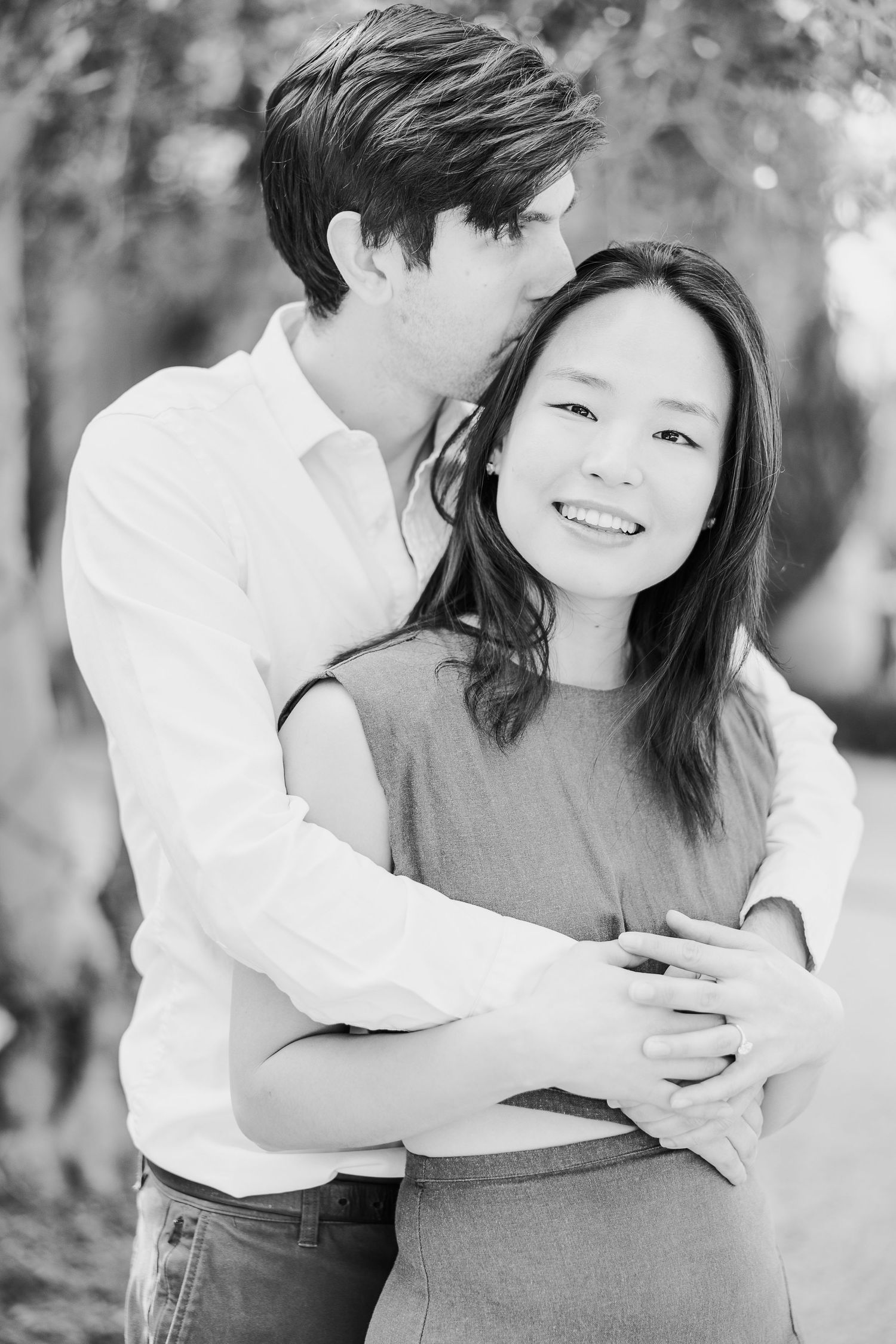 Black and white portrait of a couple embracing outdoors with natural lighting.
