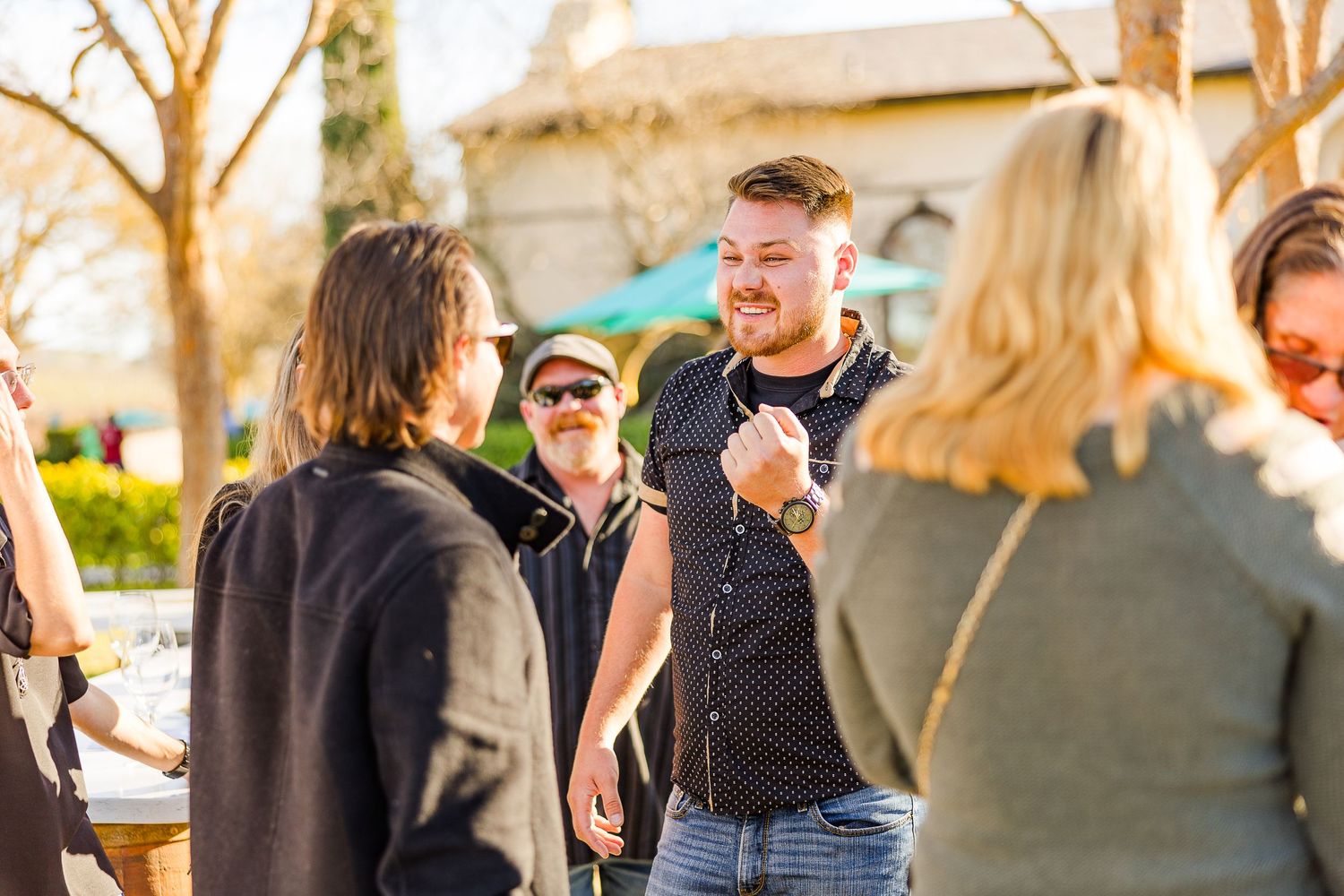 People enjoying a casual gathering at an outdoor winery with warm afternoon light.