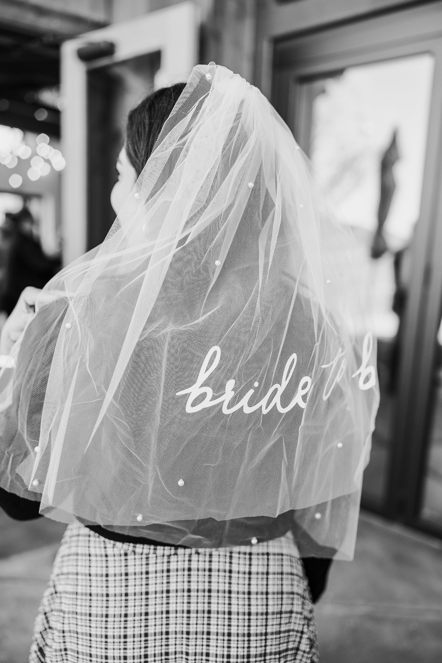 A flowing white bridal veil with 'bride' text detail shown against a checkered pattern.