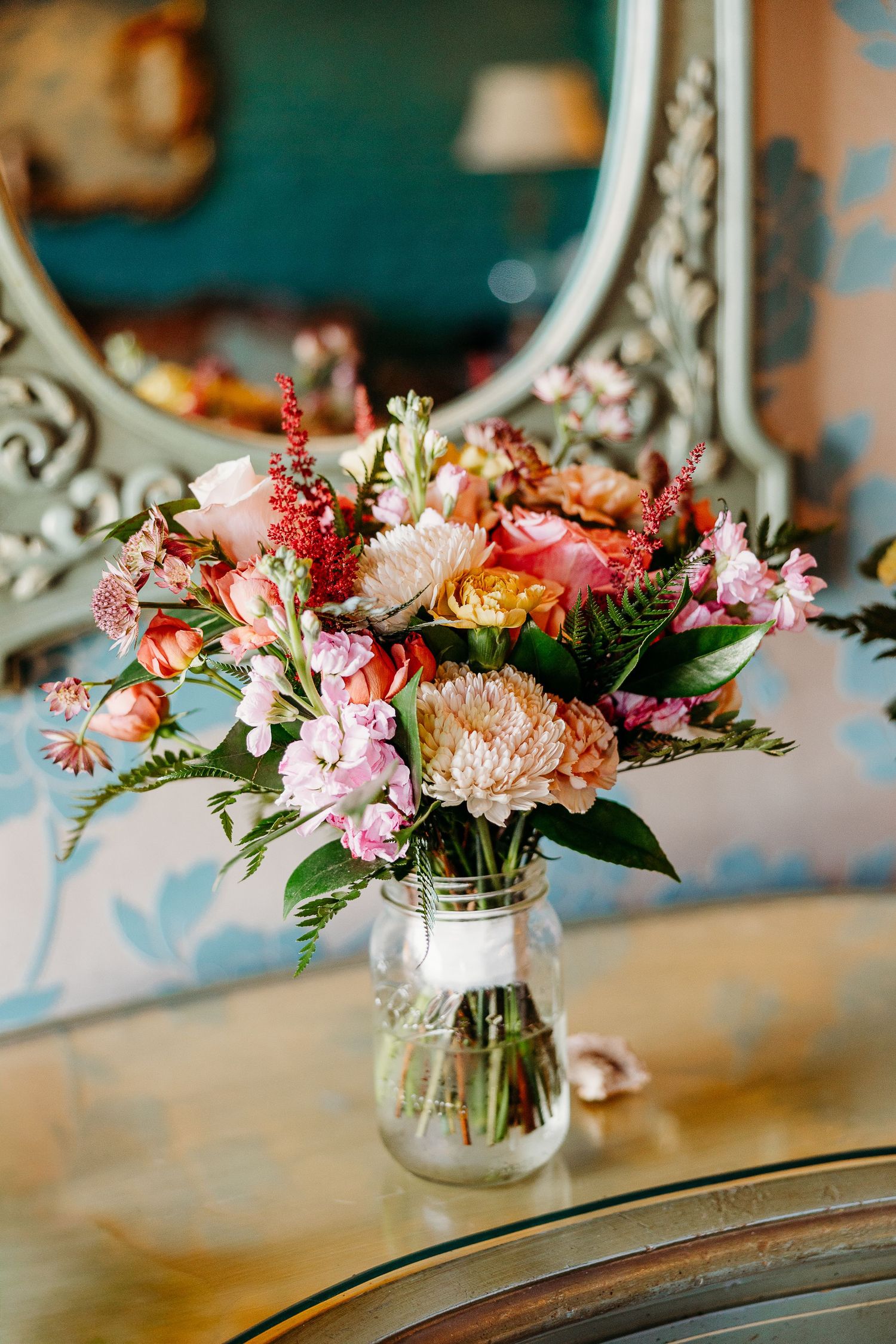 Colorful wedding bouquet with pink and coral flowers arranged in a mason jar.