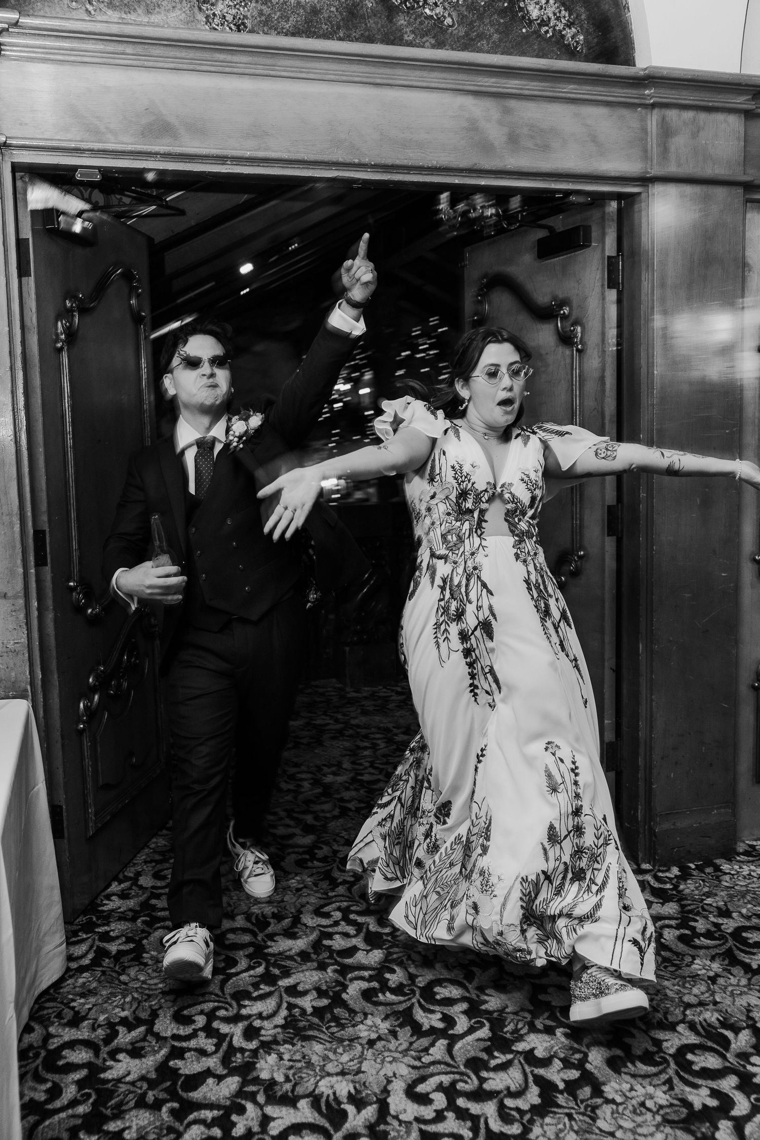 A dramatic black and white photo of a couple making expressive poses in a doorway.