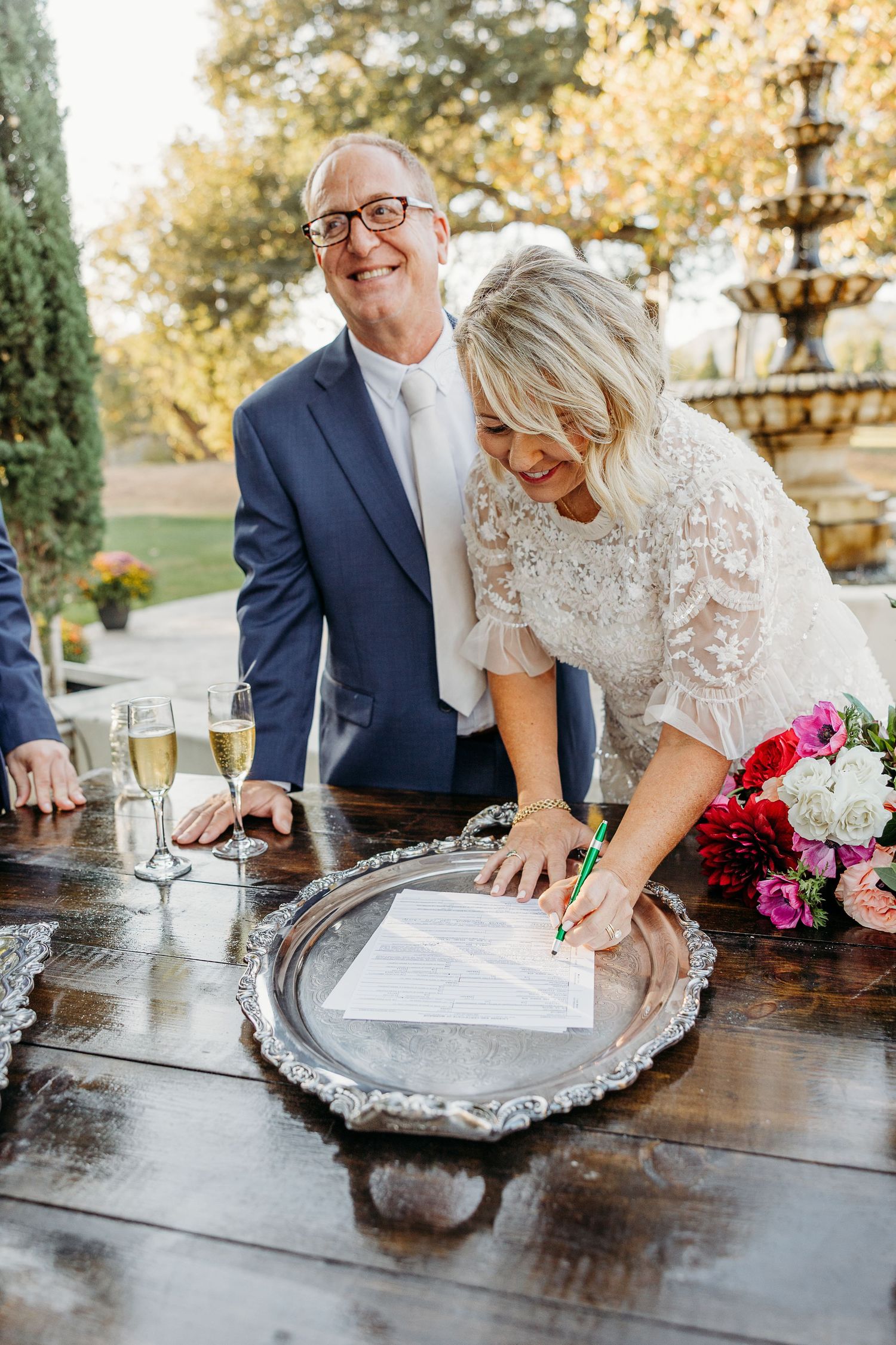 Wedding couple signing their marriage certificate on an ornate silver tray.