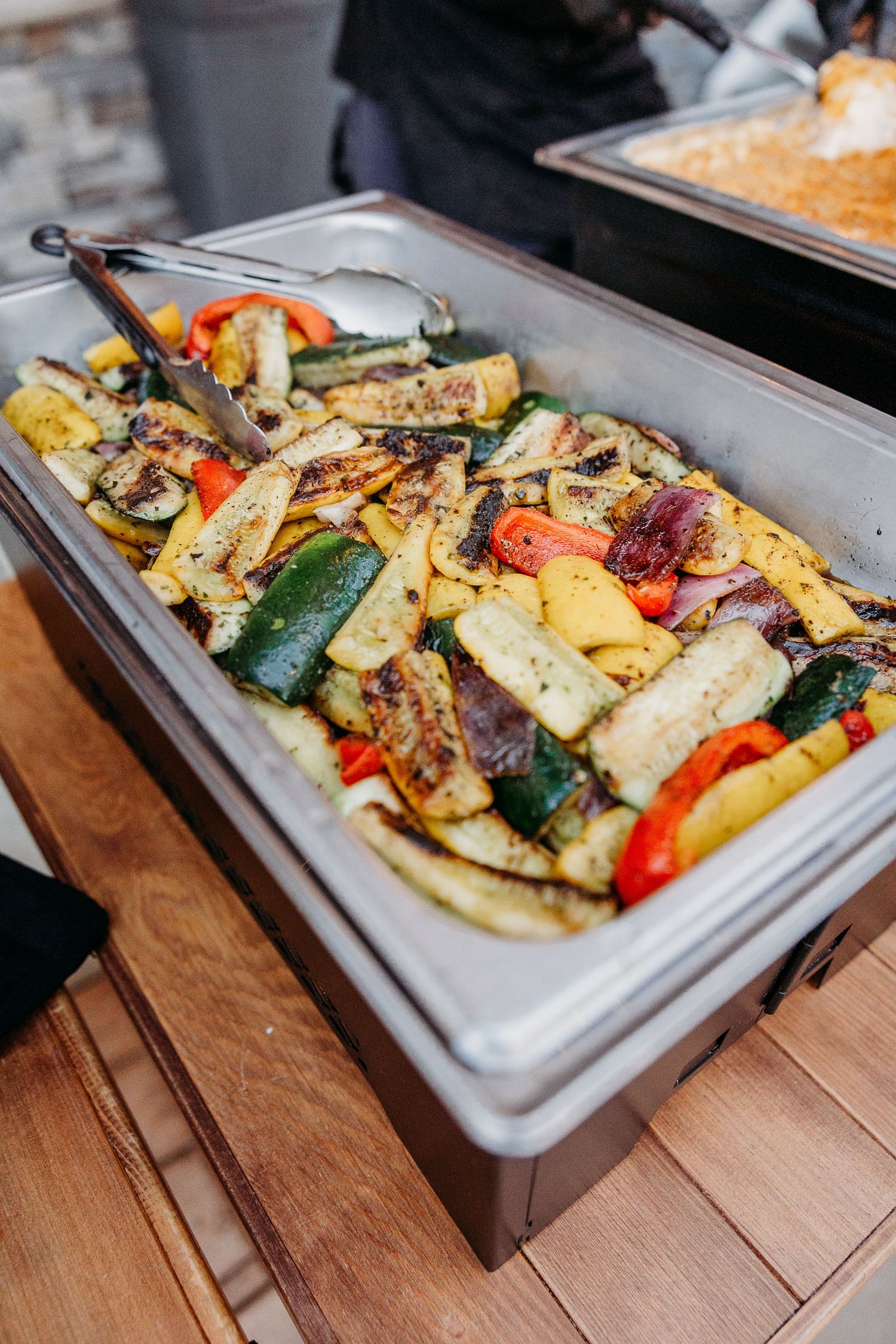 Catering tray of grilled vegetables and roasted potatoes at wedding reception.
