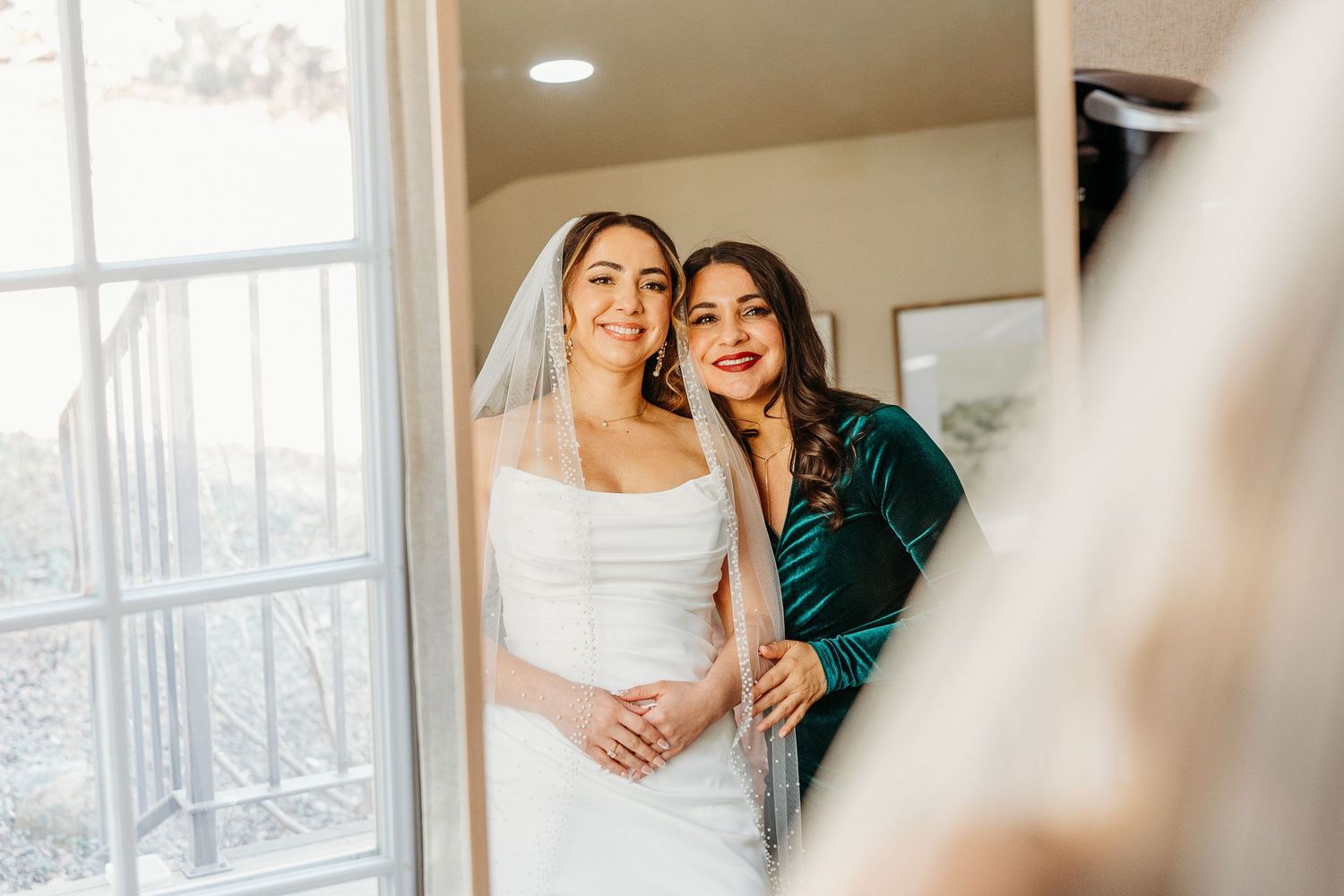 Couple shares intimate moment in bright indoor setting during wedding preparations.