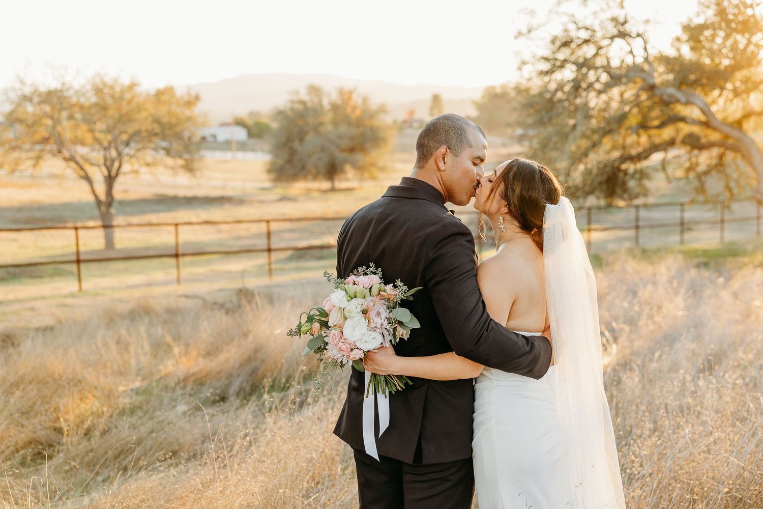 Romantic sunset wedding portraits in golden field with floral bouquet details.