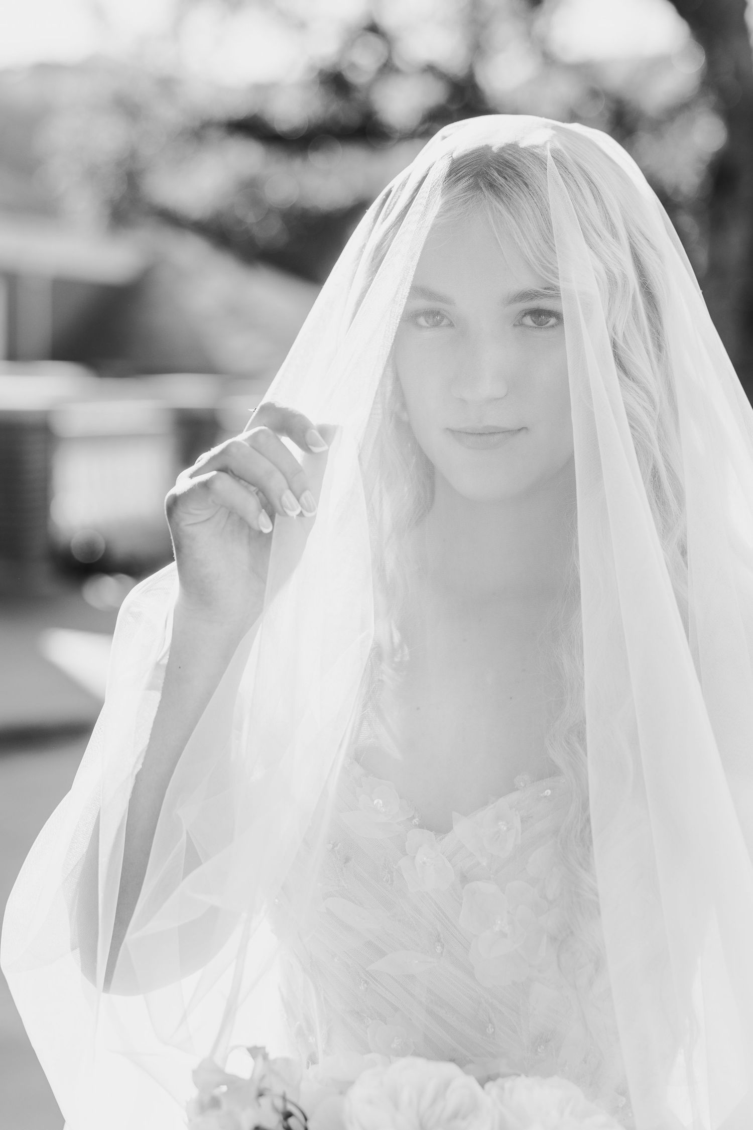 A bride in a white veil smiles softly in a series of romantic wedding portraits captured in natural light.