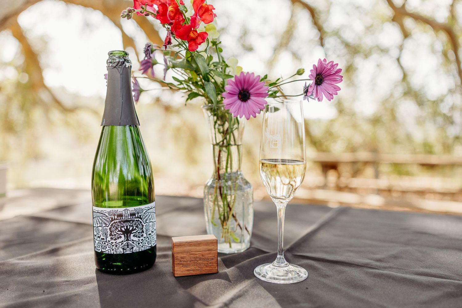 Elegant table setting with red flowers and wine glasses arranged outdoors.