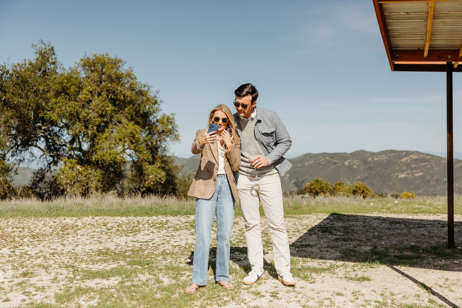 Couple walking together on a scenic path with mountains visible in the background.