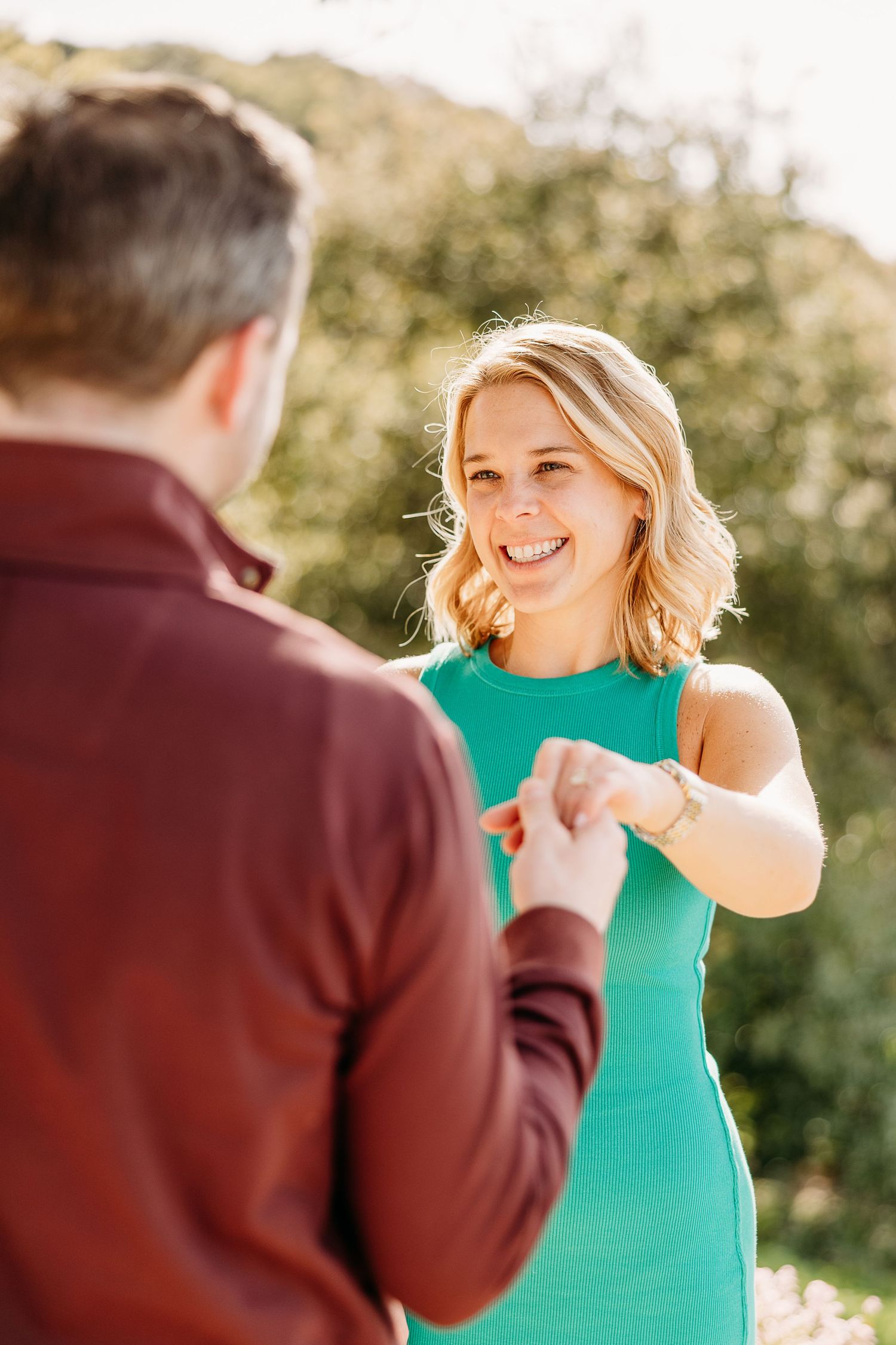 Playful couple interacts with laughter and animated gestures during an outdoor portrait session.