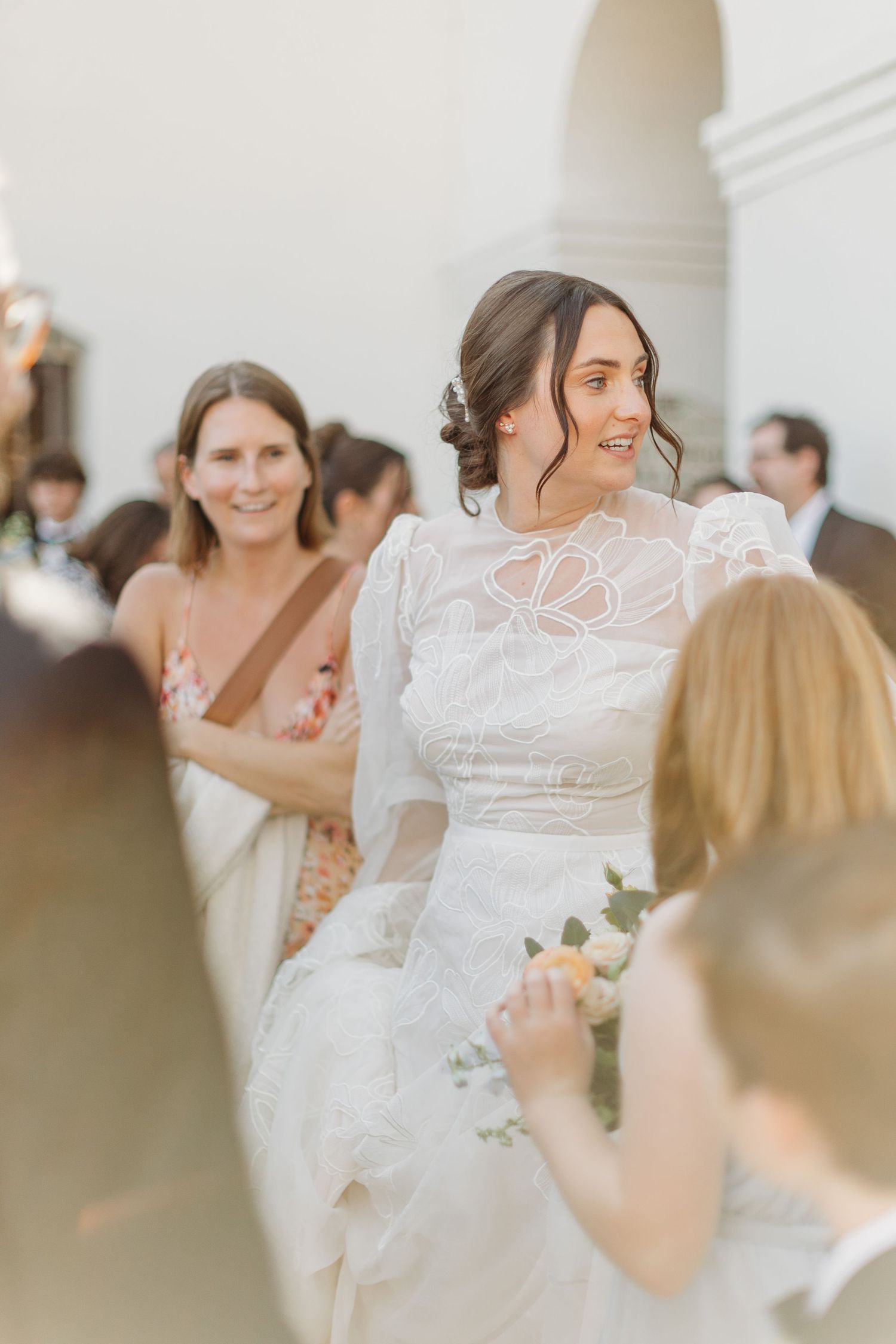Wedding celebration in progress under white arched hallway with elegant decor outside Mission San Luis Obispo.