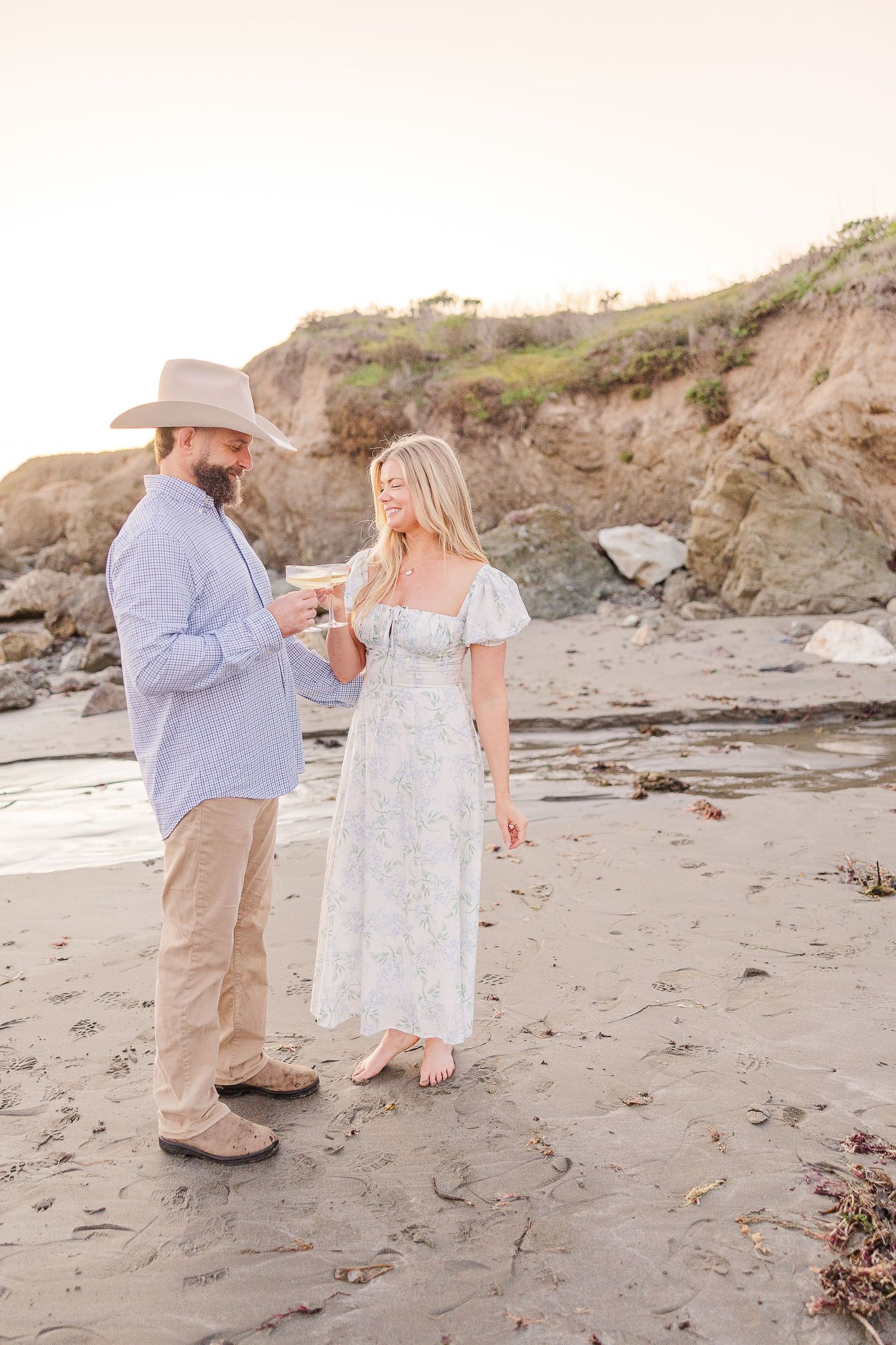 A tender moment captured on a beach as a couple stands together at golden hour.