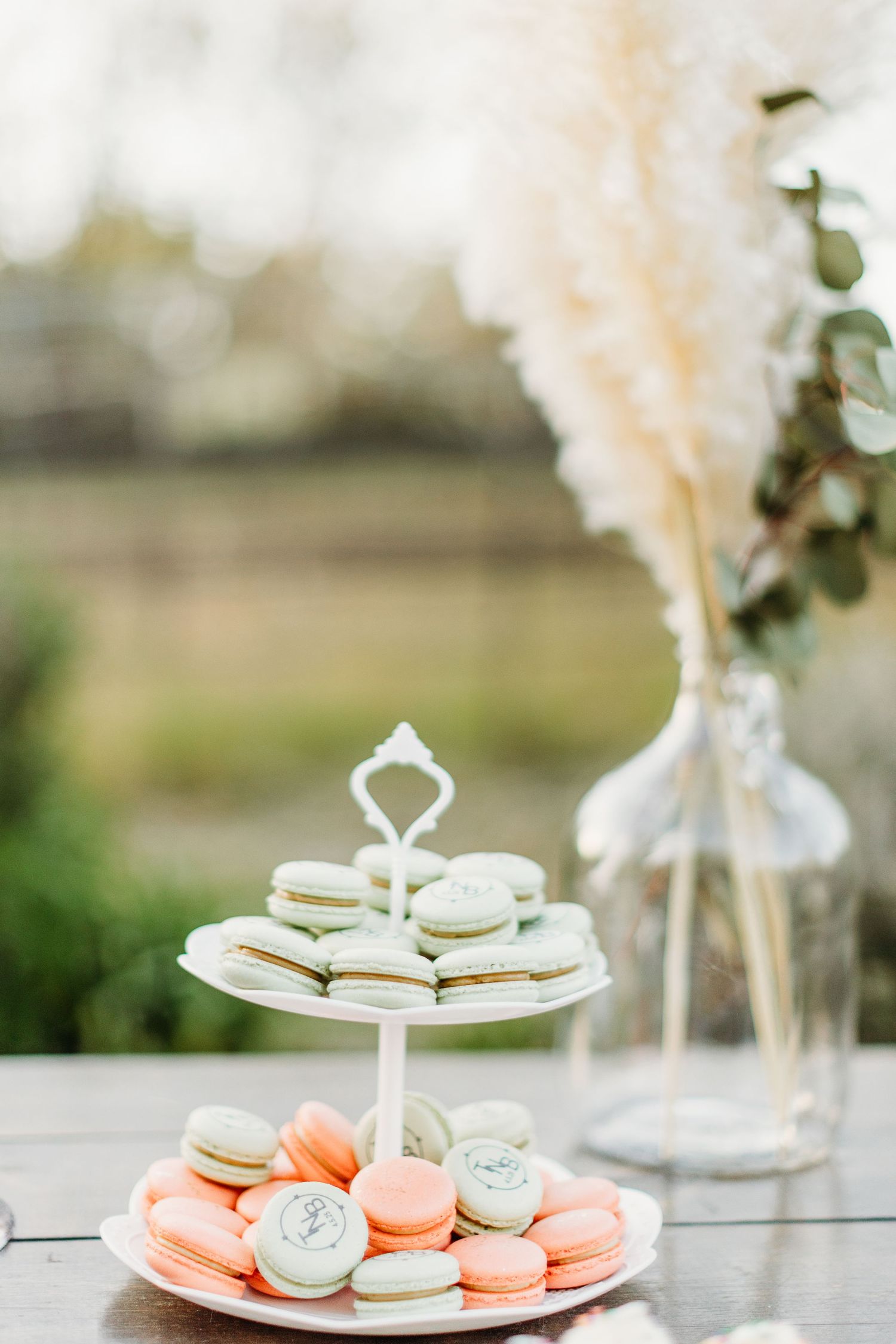Two-tiered serving stand with colorful macarons in pink and mint green shades.