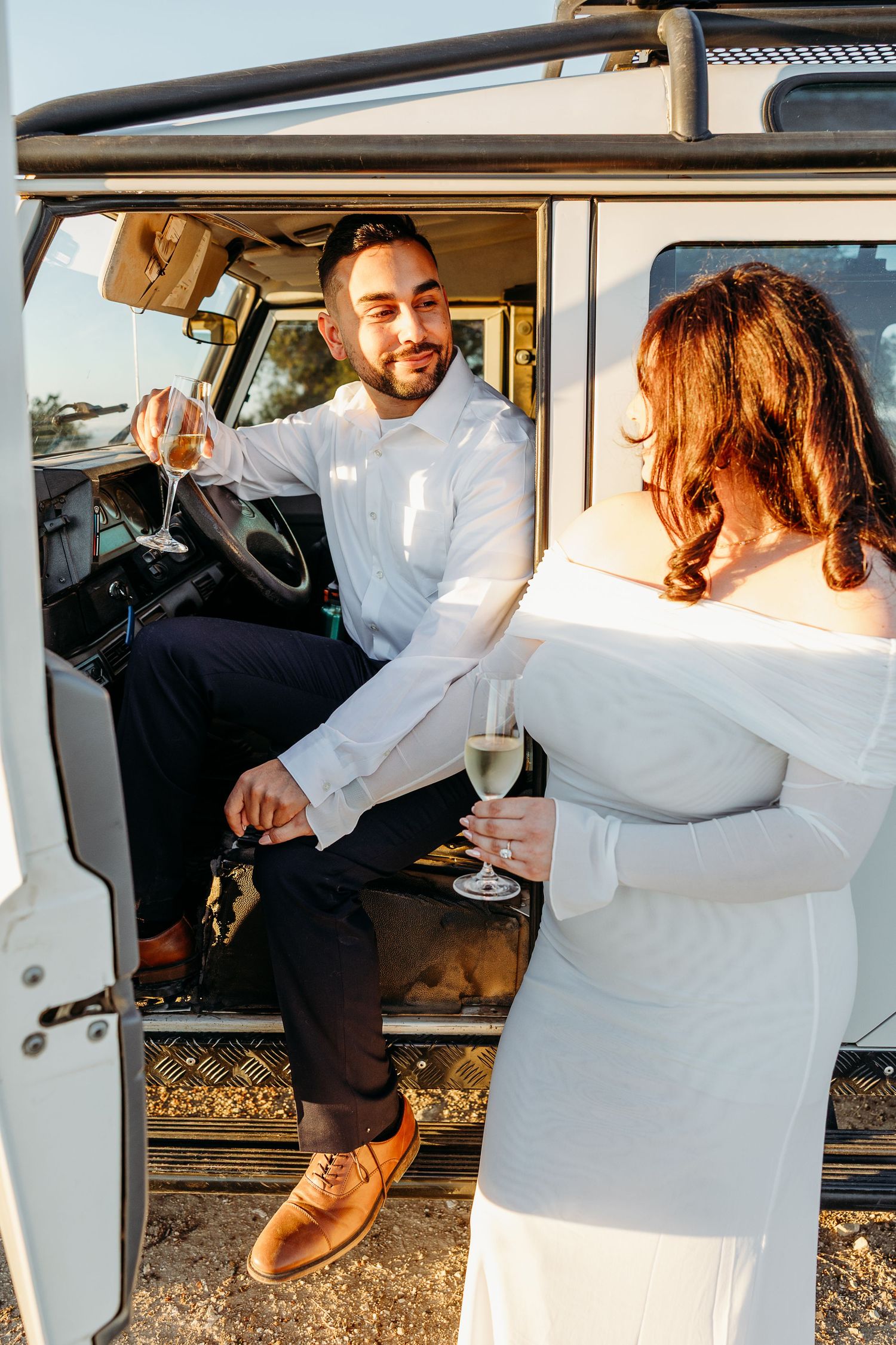 A group celebrates inside a vintage white van during sunset.