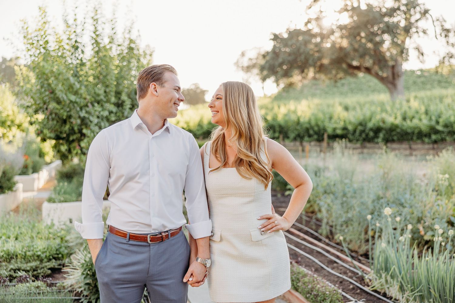 A couple shares a romantic moment together in a garden setting during golden hour.