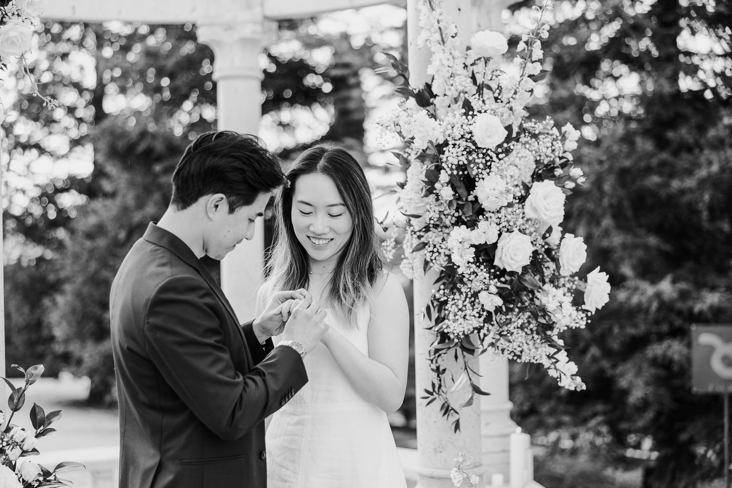 Black and white wedding photography capturing romantic moments under floral-decorated arches.