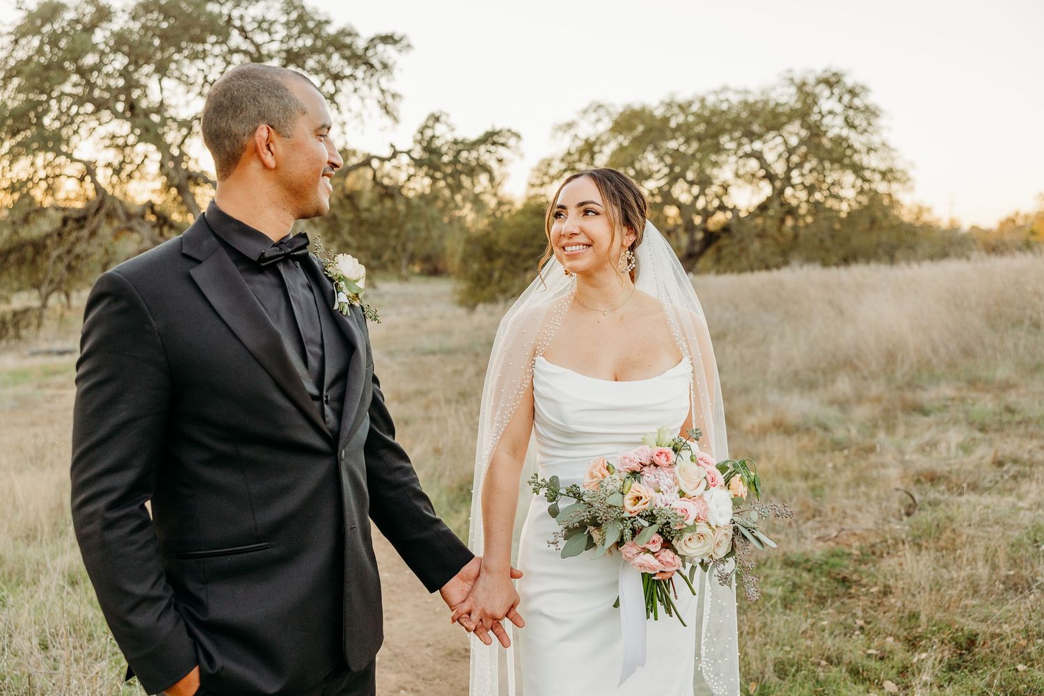 Romantic outdoor wedding portraits in a rustic field during golden hour.