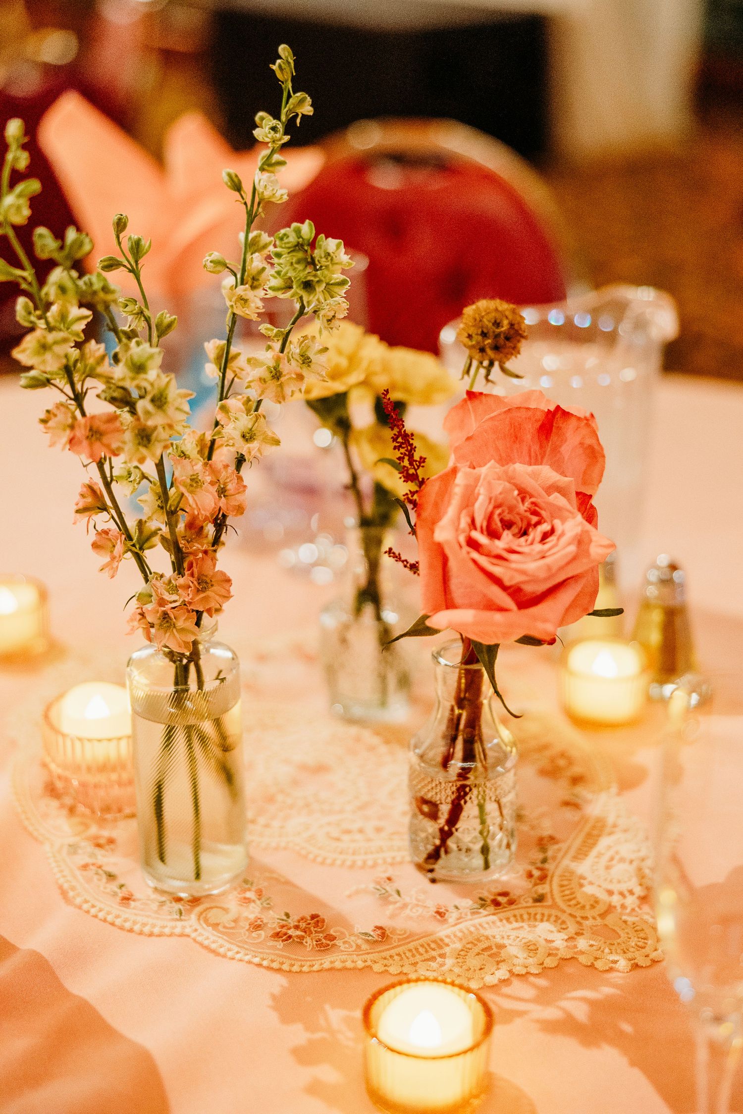 Elegant table settings with pink roses and candlelight creating a romantic reception atmosphere.