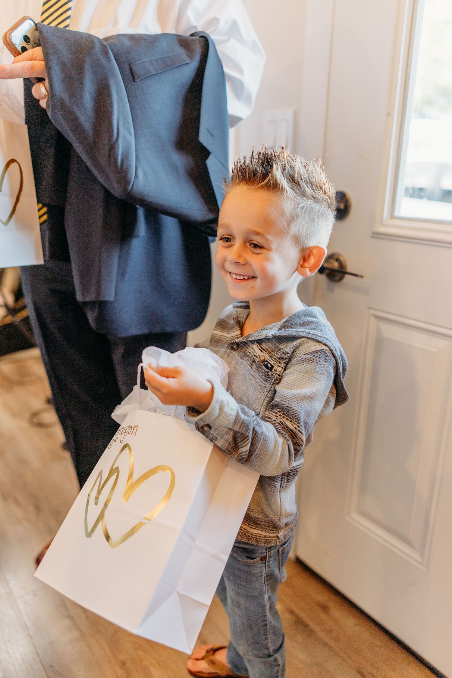 A young child holding a white shopping bag with excitement on their face.