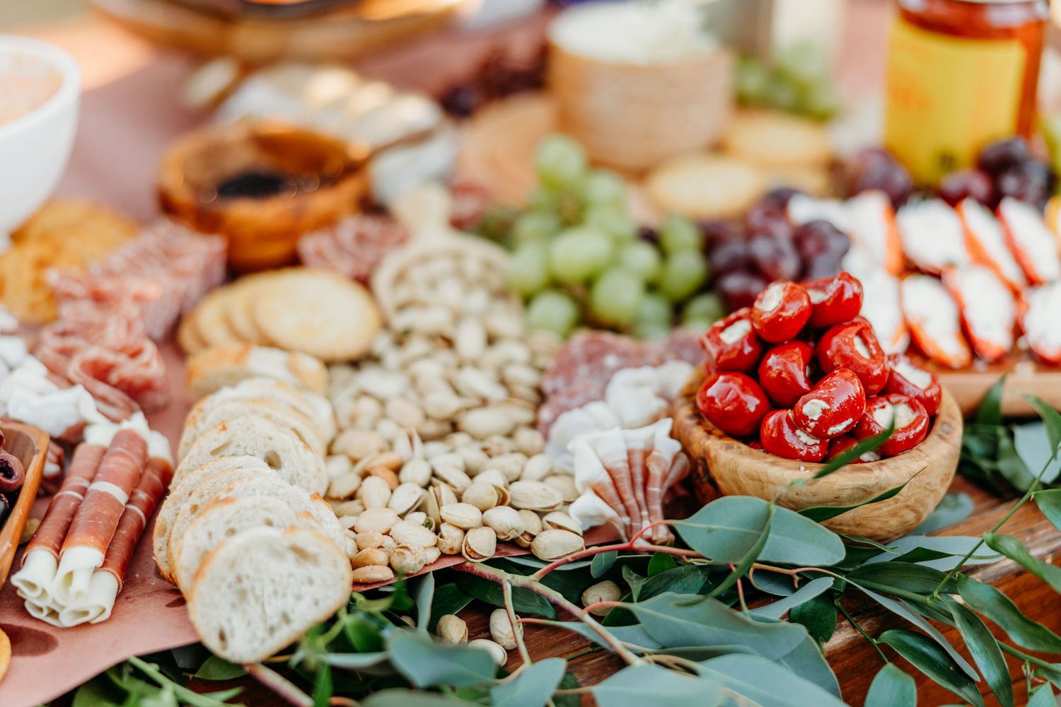 Elegant charcuterie board with crackers, nuts, fruit, and greenery arranged for a special event.