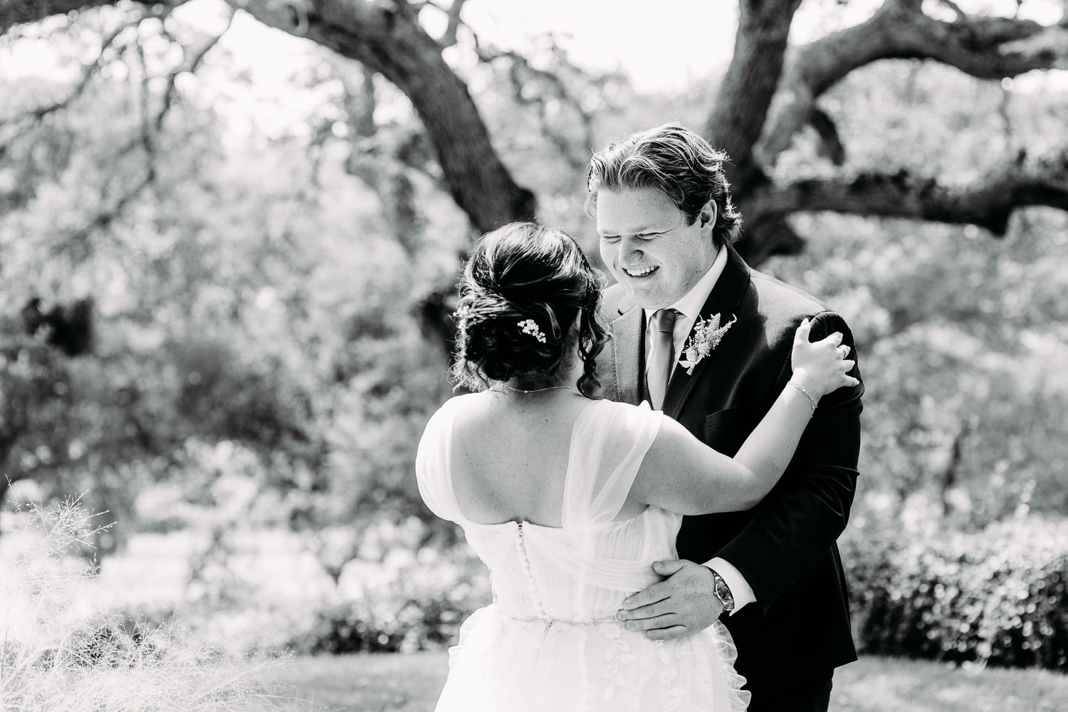 A black and white romantic moment captured between newlyweds under a tree.