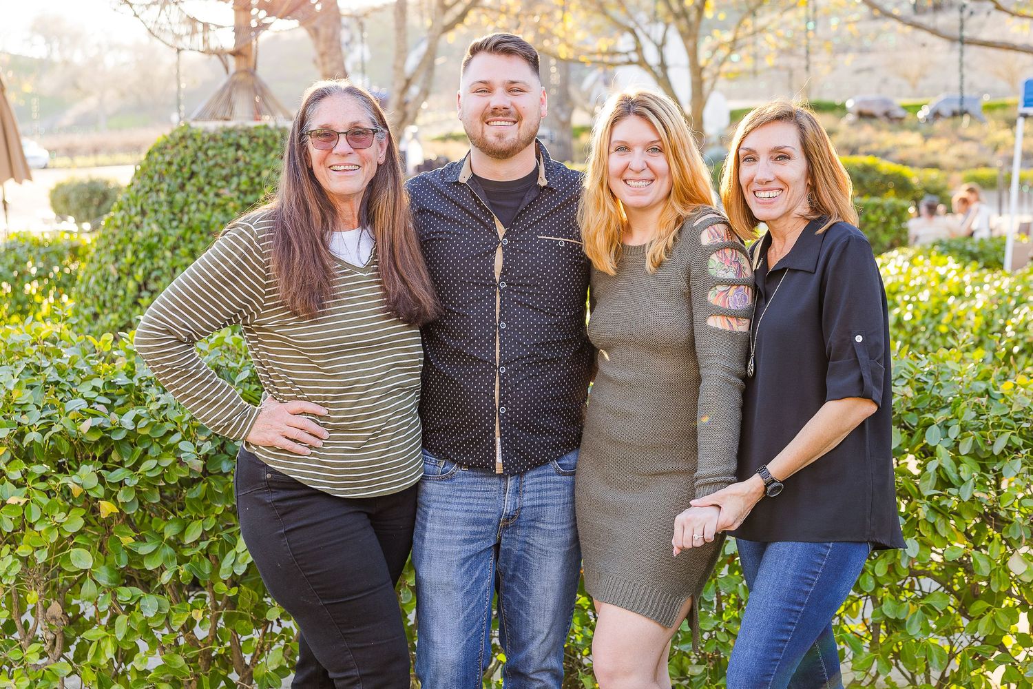 Small group portrait in front of garden greenery on sunny day.