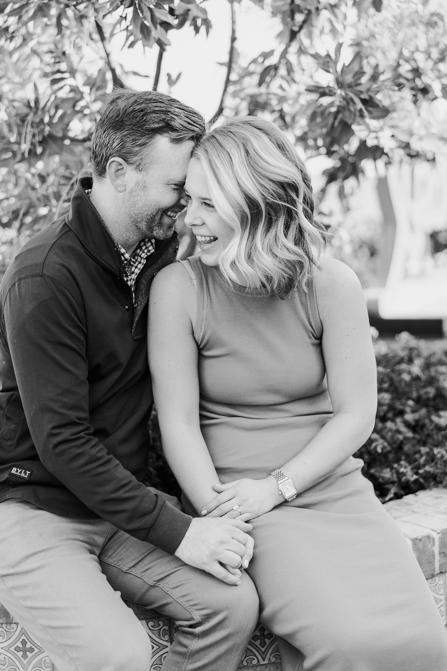 A couple shares an intimate moment while sitting together outdoors in a romantic black and white photo series.