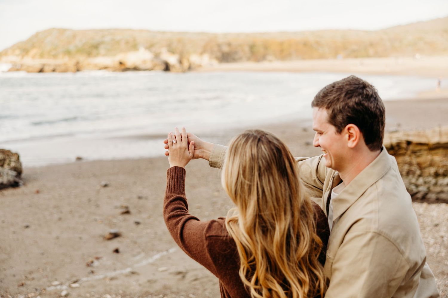 A couple enjoys a tender moment together on a scenic beach at dusk.