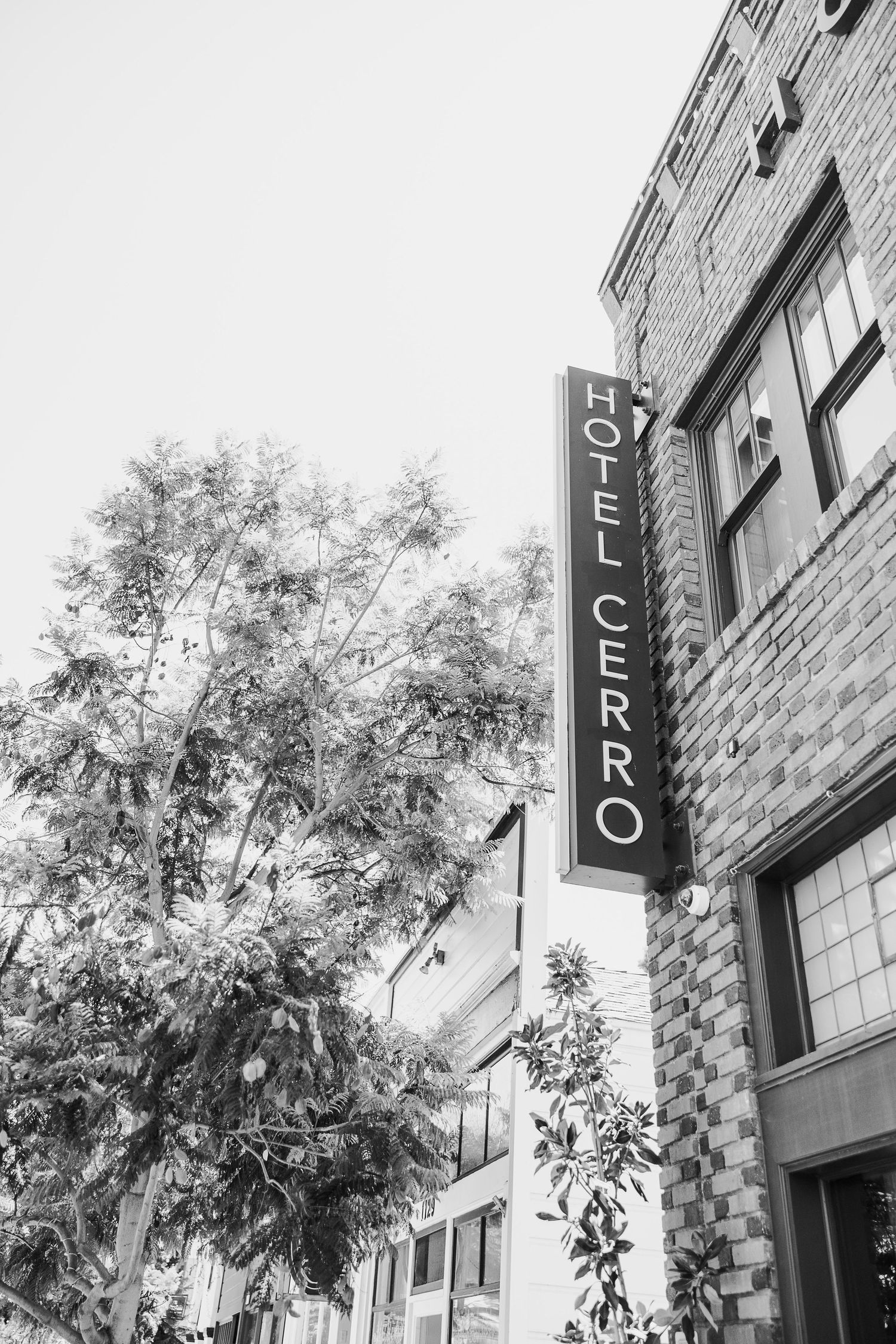 Black and white image of Hotel Cerro sign mounted on brick building exterior.