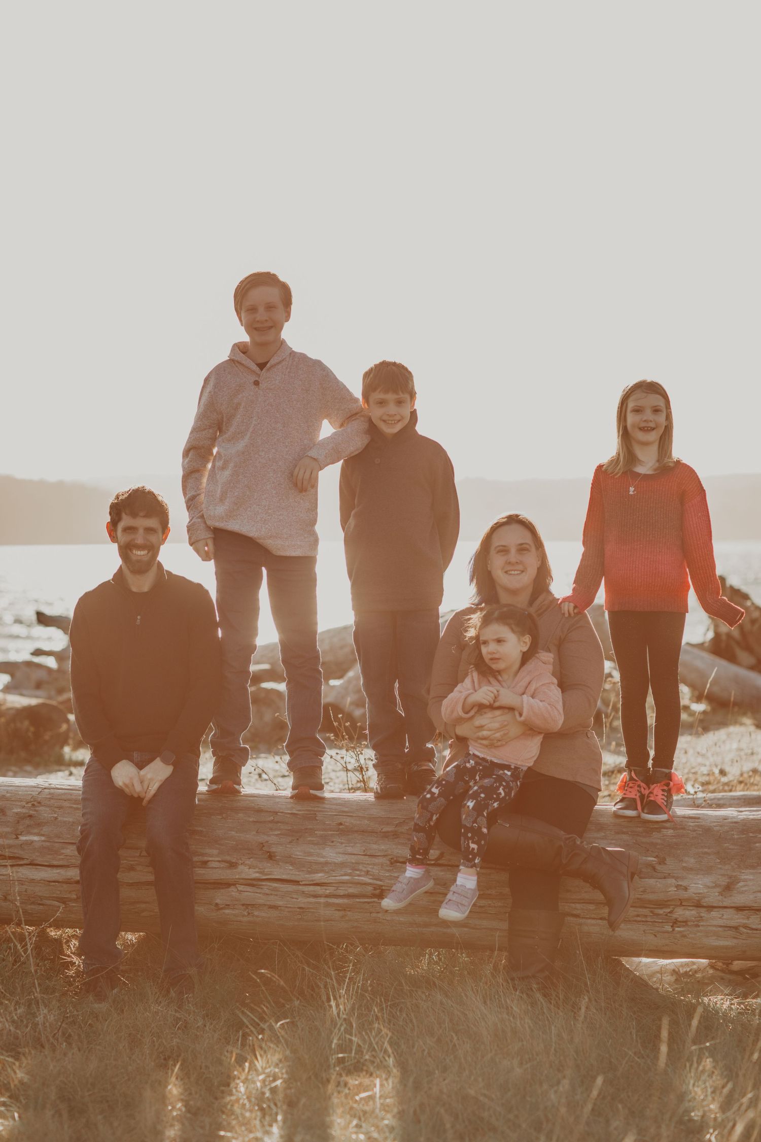 A family group poses together on rocky terrain at sunset with warm lighting and casual attire.