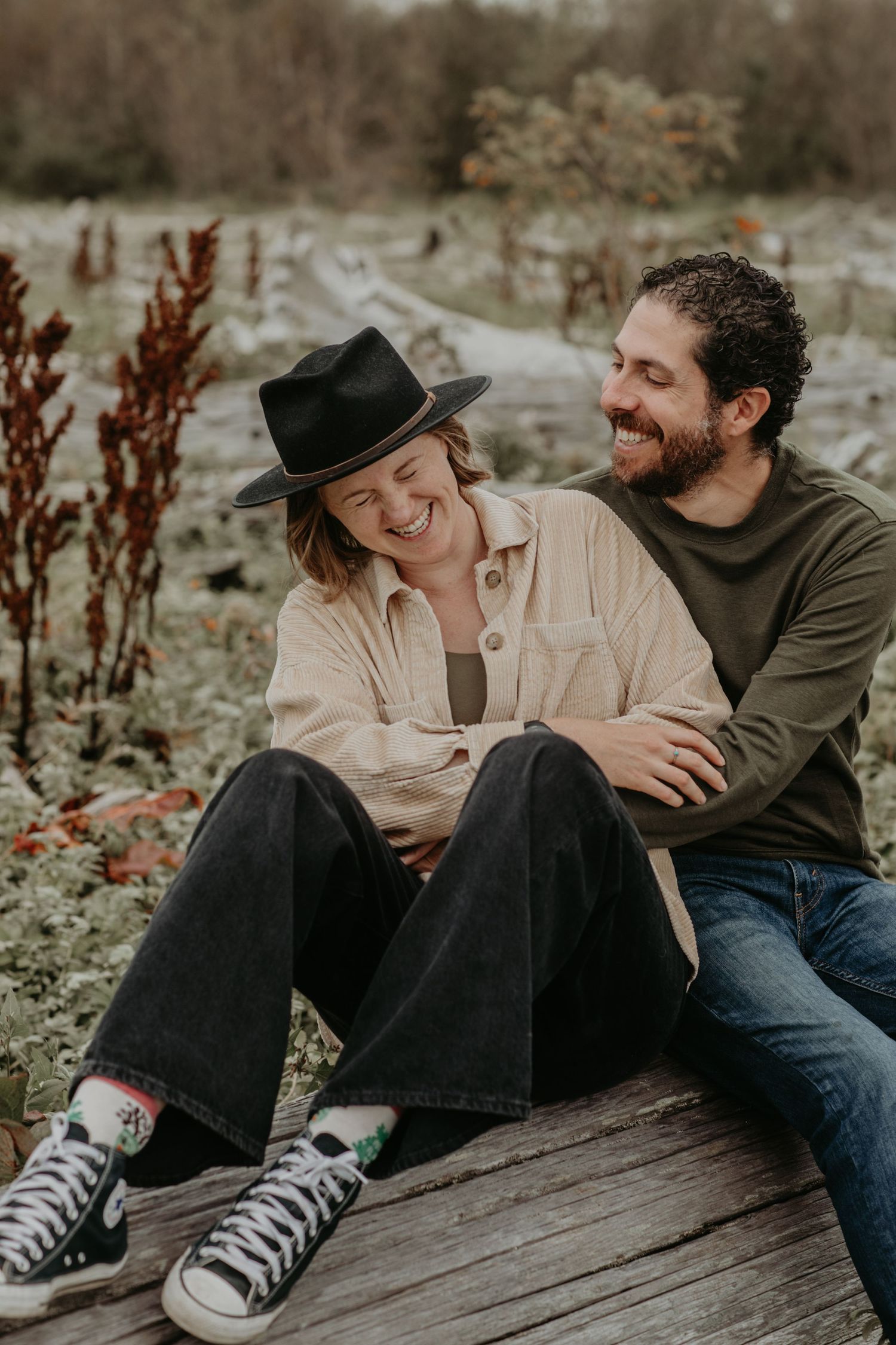 Couple sitting together outdoors sharing a romantic moment on wooden deck with autumn foliage.