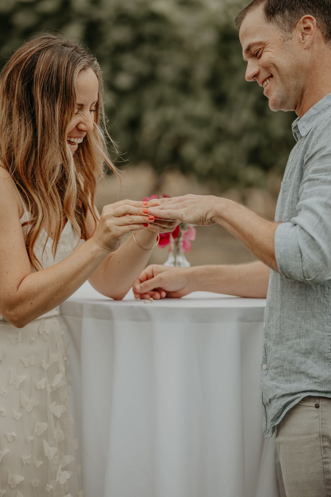 A couple shares a joyful moment during an engagement photoshoot in a natural outdoor setting.