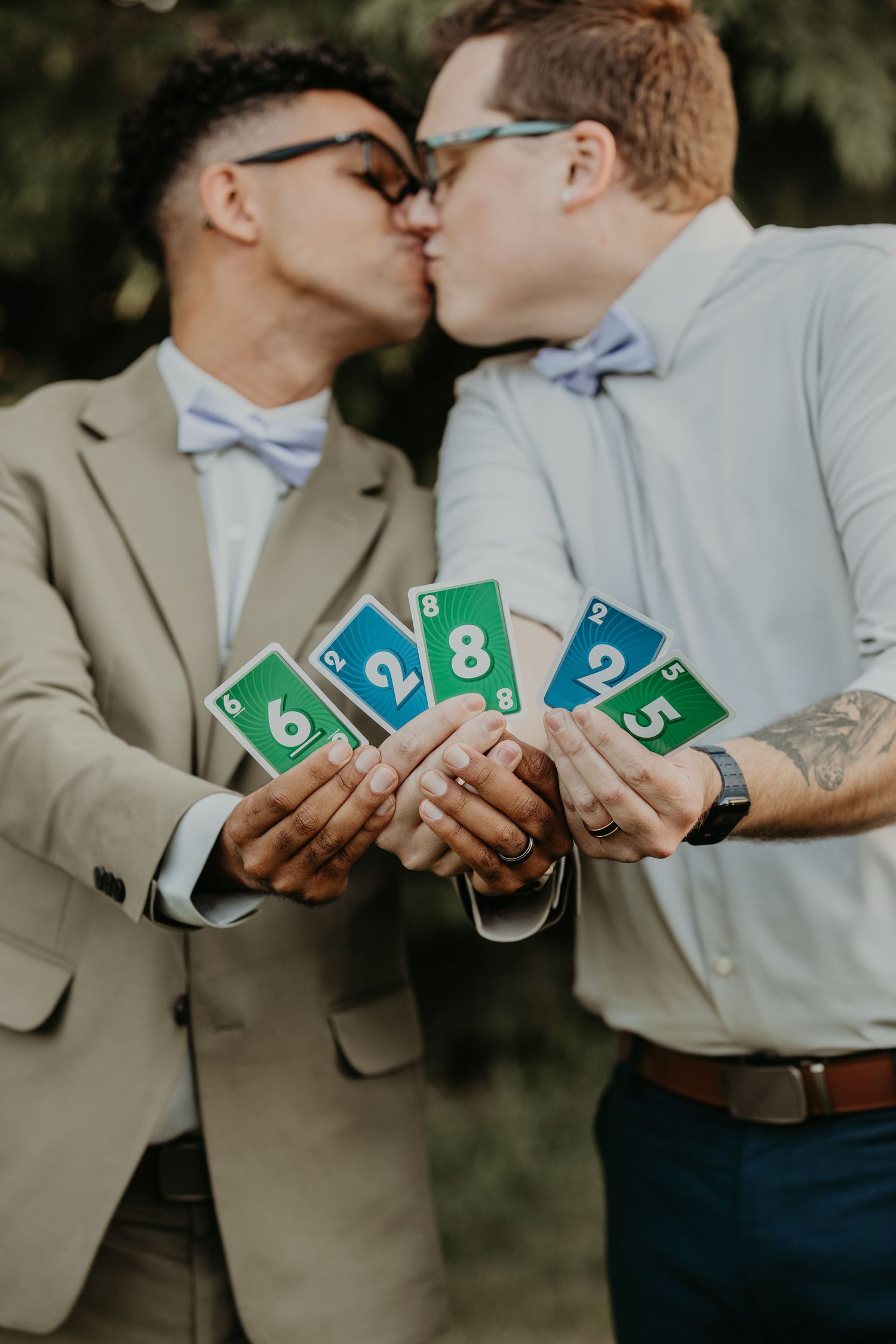 Two people in formal wear holding Uno cards showing numbers while standing close together and sharing a romantic moment.