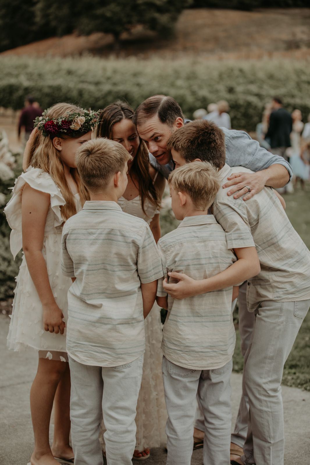 Wedding group huddles together in a joyful moment during an outdoor celebration.