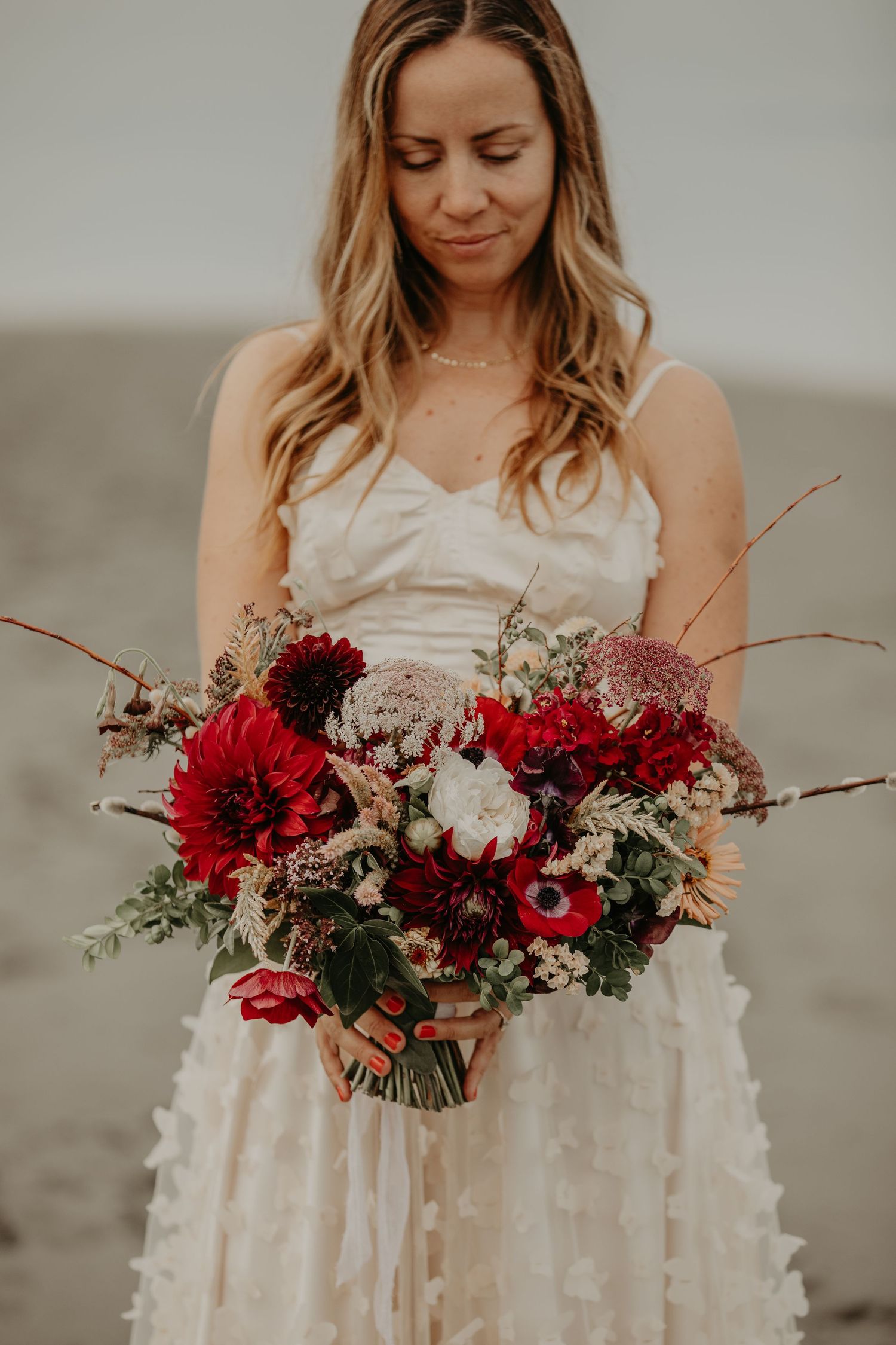 A close-up series of a bridal bouquet featuring deep red and white flowers with rustic branches and greenery.