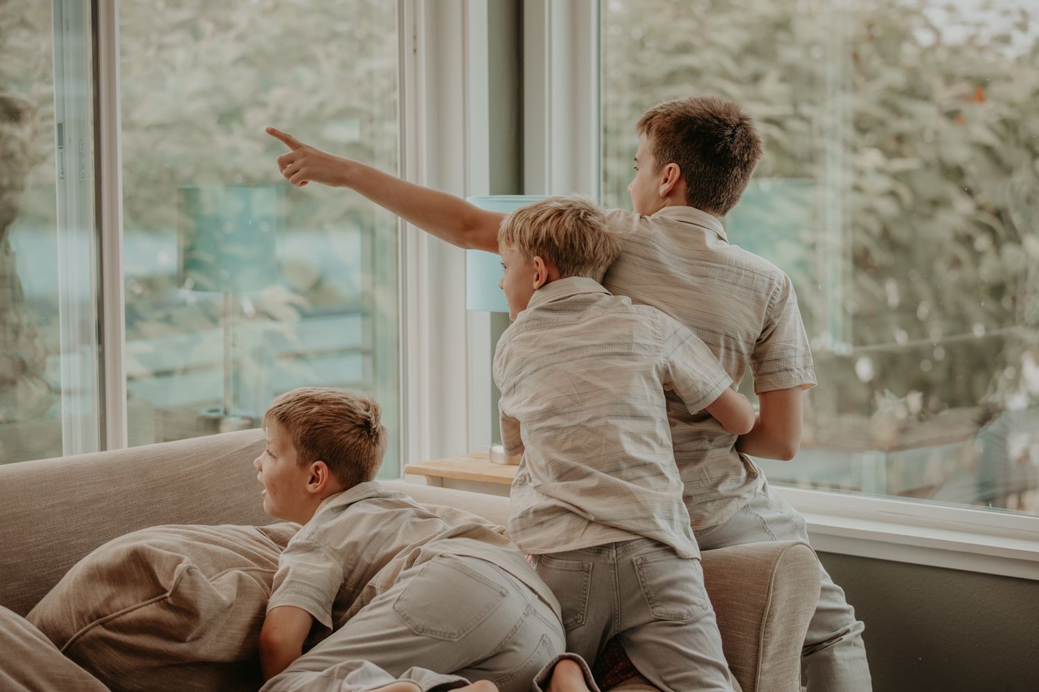 A series of photos showing energetic children playing and jumping on a couch in a sunlit living room.