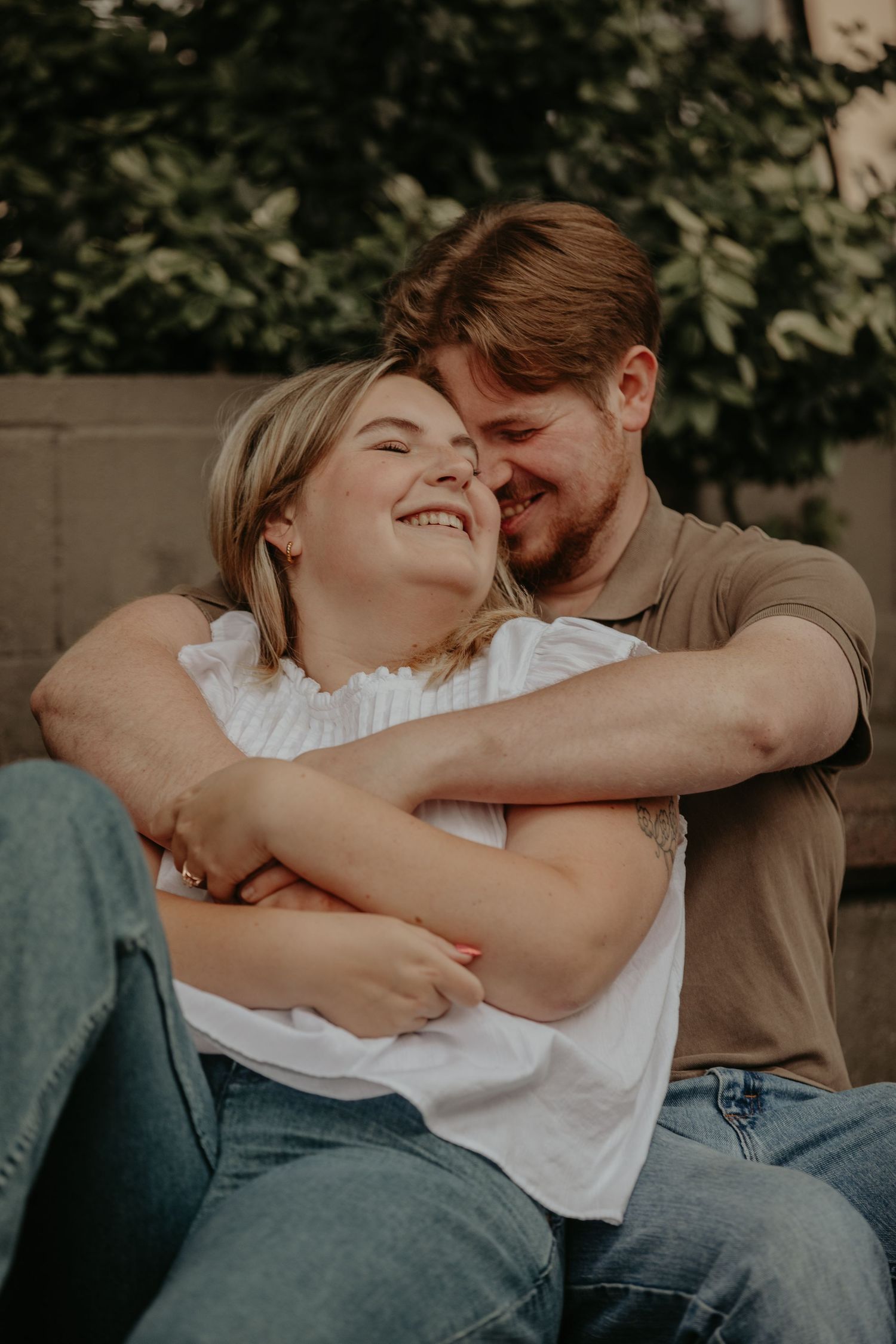 A tender moment shared between a couple as they embrace and laugh together outdoors.