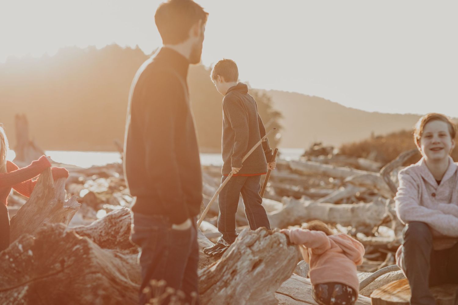 A silhouetted group stands on rocks during golden hour with sun-drenched scenery in the background.