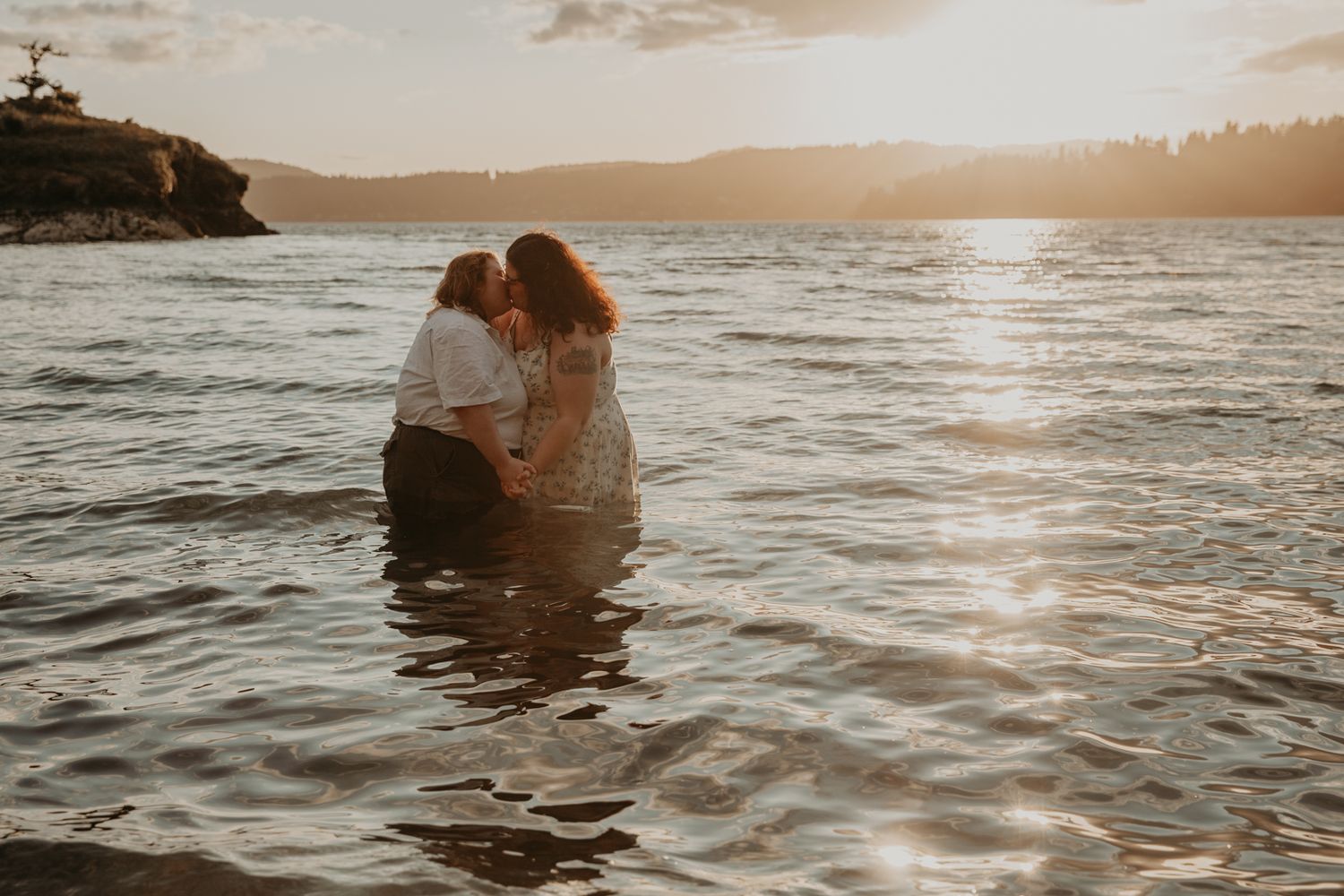 Silhouetted figures sit by the water's edge during golden hour as sunlight sparkles on the ocean waves.