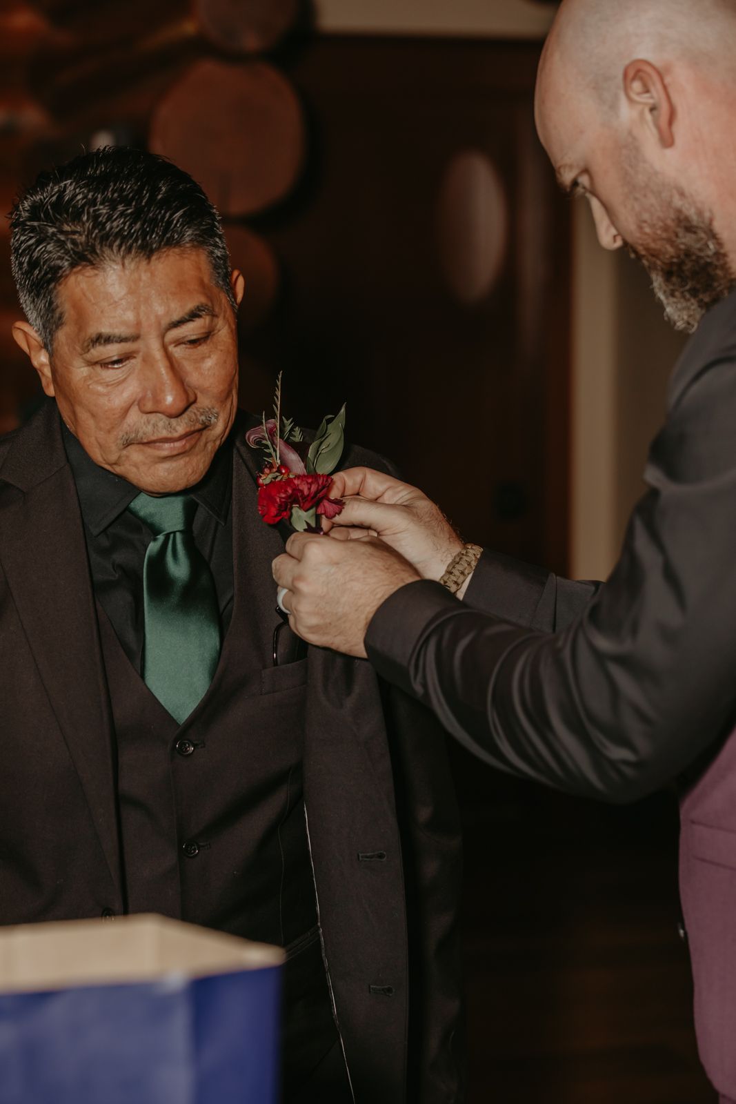 A sequence showing someone getting a red boutonniere pinned to their black suit jacket at a formal event.
