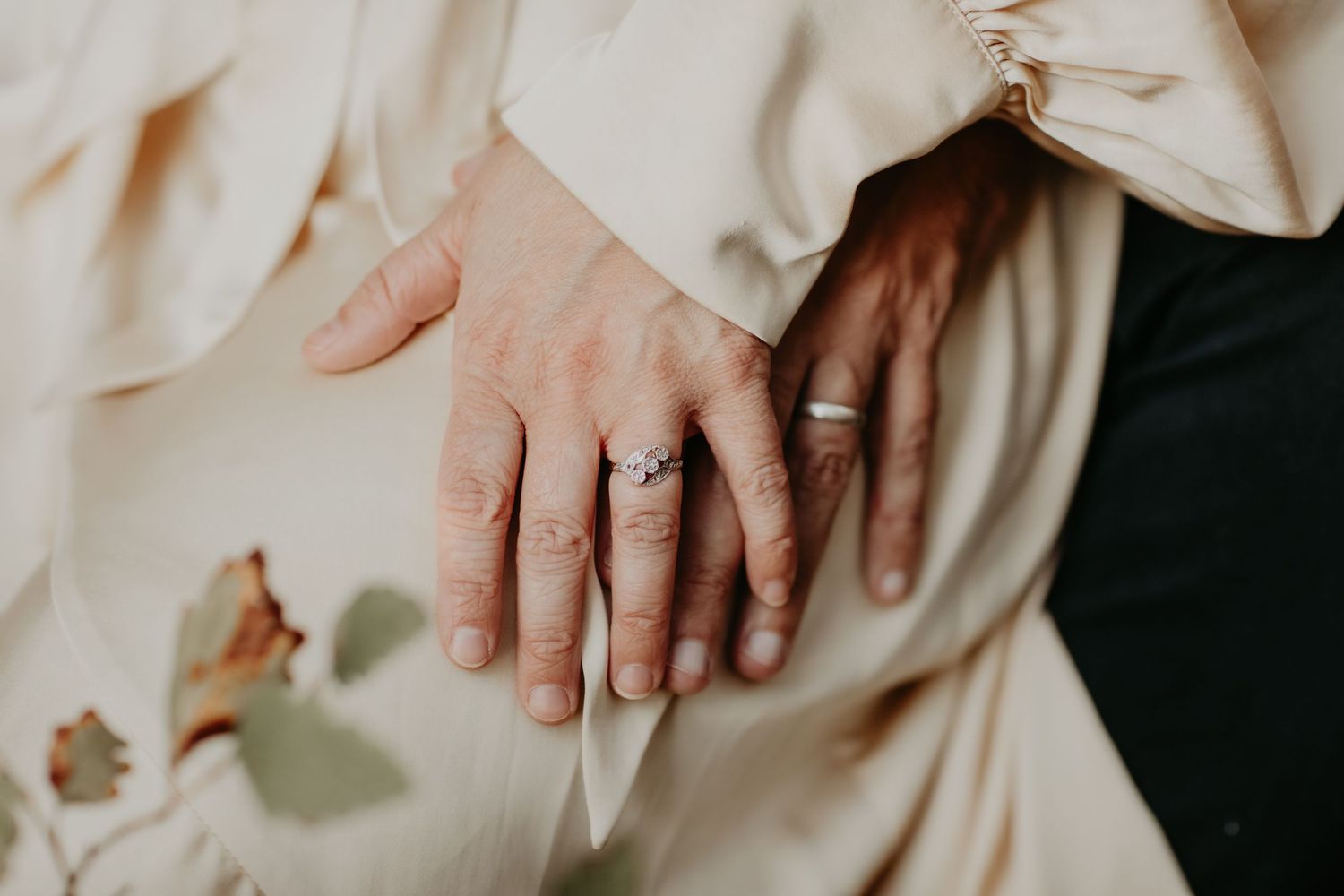 Close-up shot of hands with wedding rings holding a white fabric.