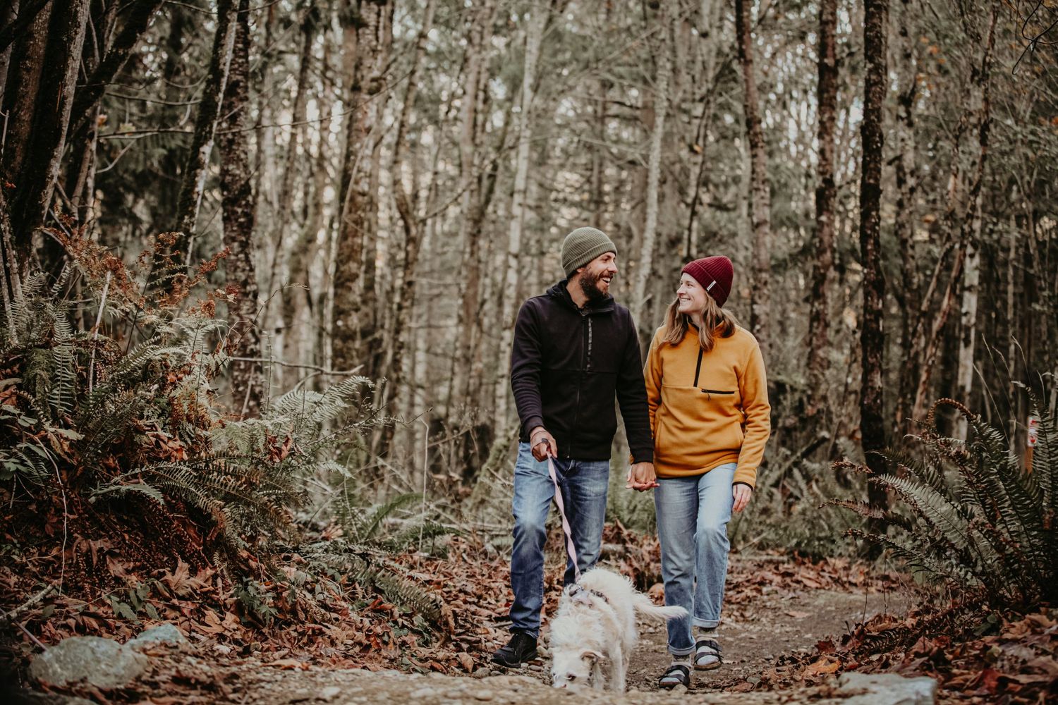 A family and their dog enjoy an autumn stroll along a wooded forest trail in the Pacific Northwest.