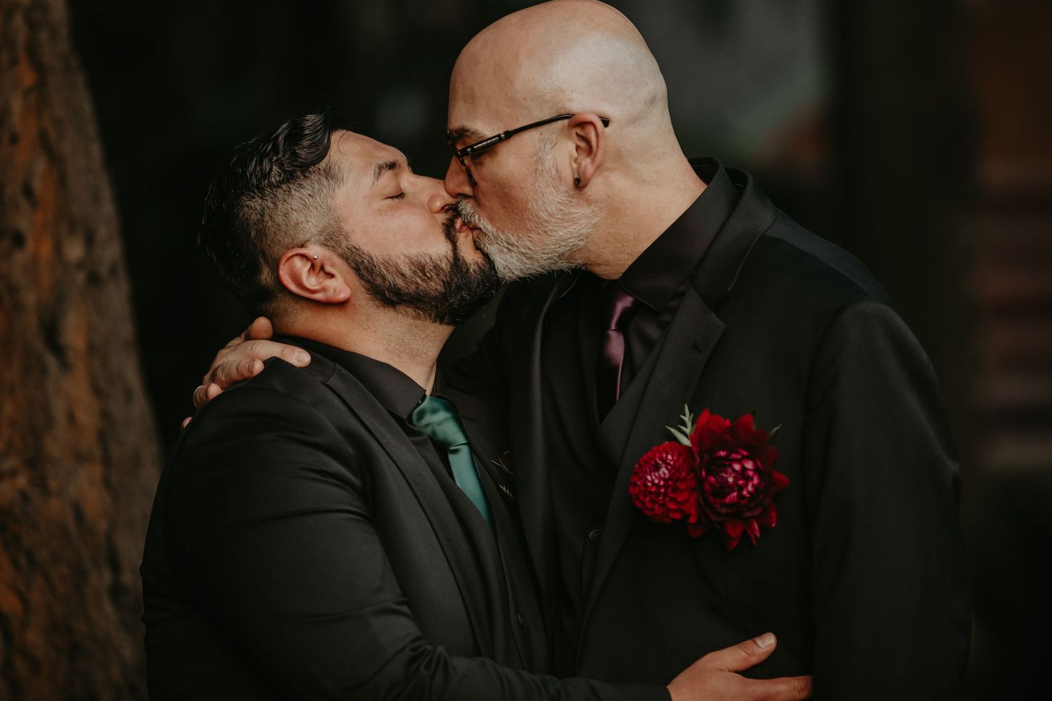 A romantic moment captured in a forest setting with red floral accents.