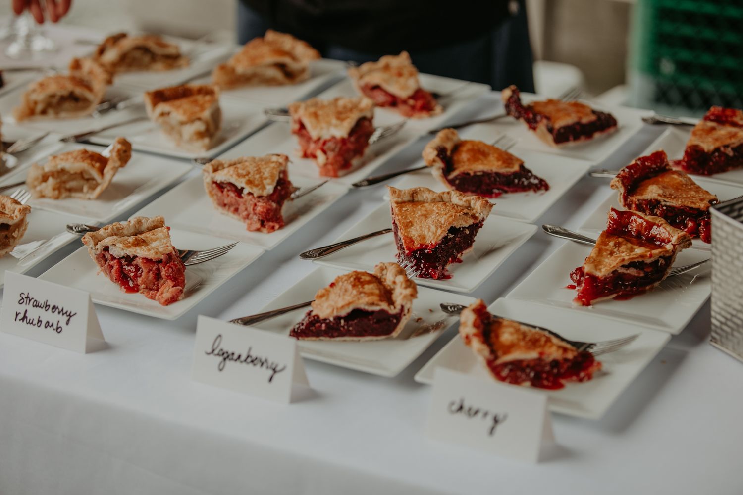 Rows of plated desserts arranged on a white surface with small name cards beside each serving.