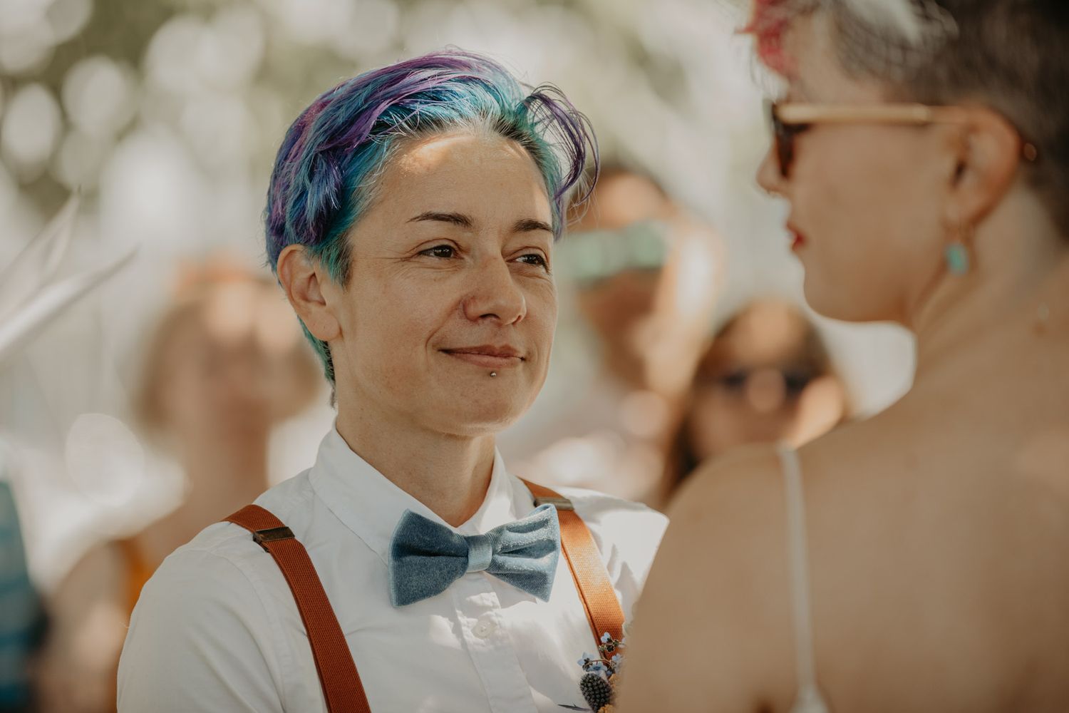 Two people with colorful hair share a joyful moment during a wedding celebration.