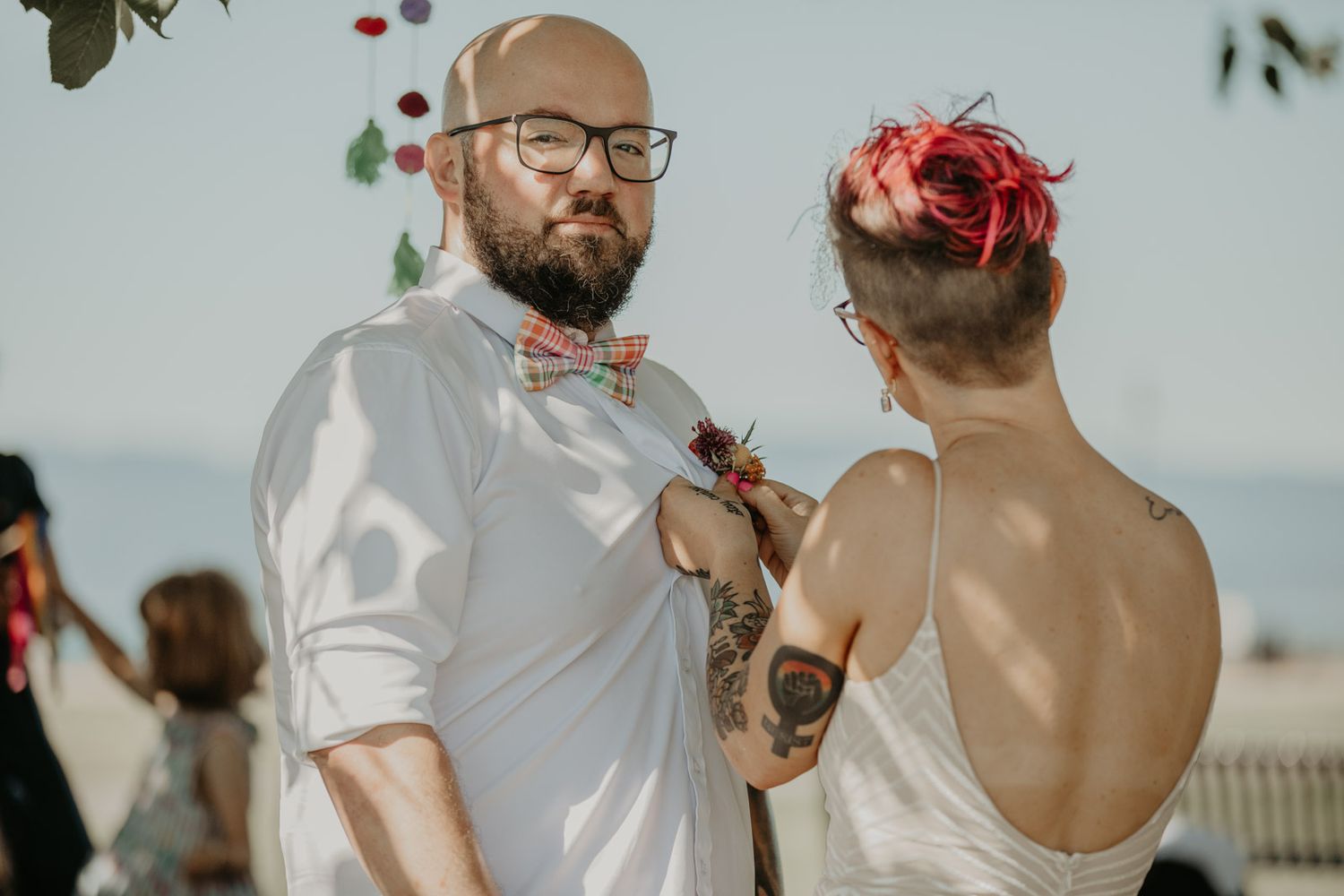 A couple shares an intimate moment outdoors with green foliage and red berries in the background.