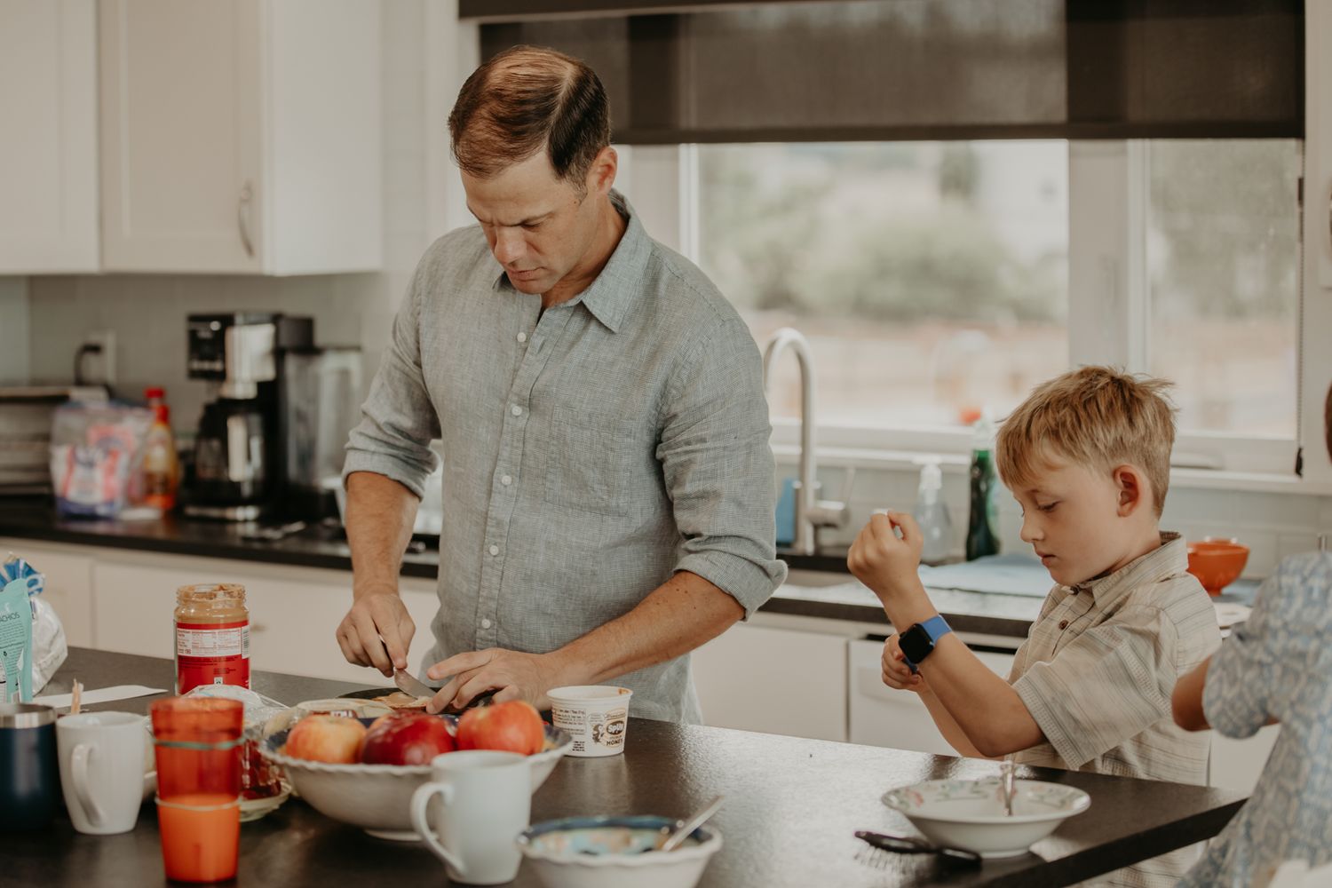 A family gathers around a kitchen counter to prepare and eat a meal together in a modern home.