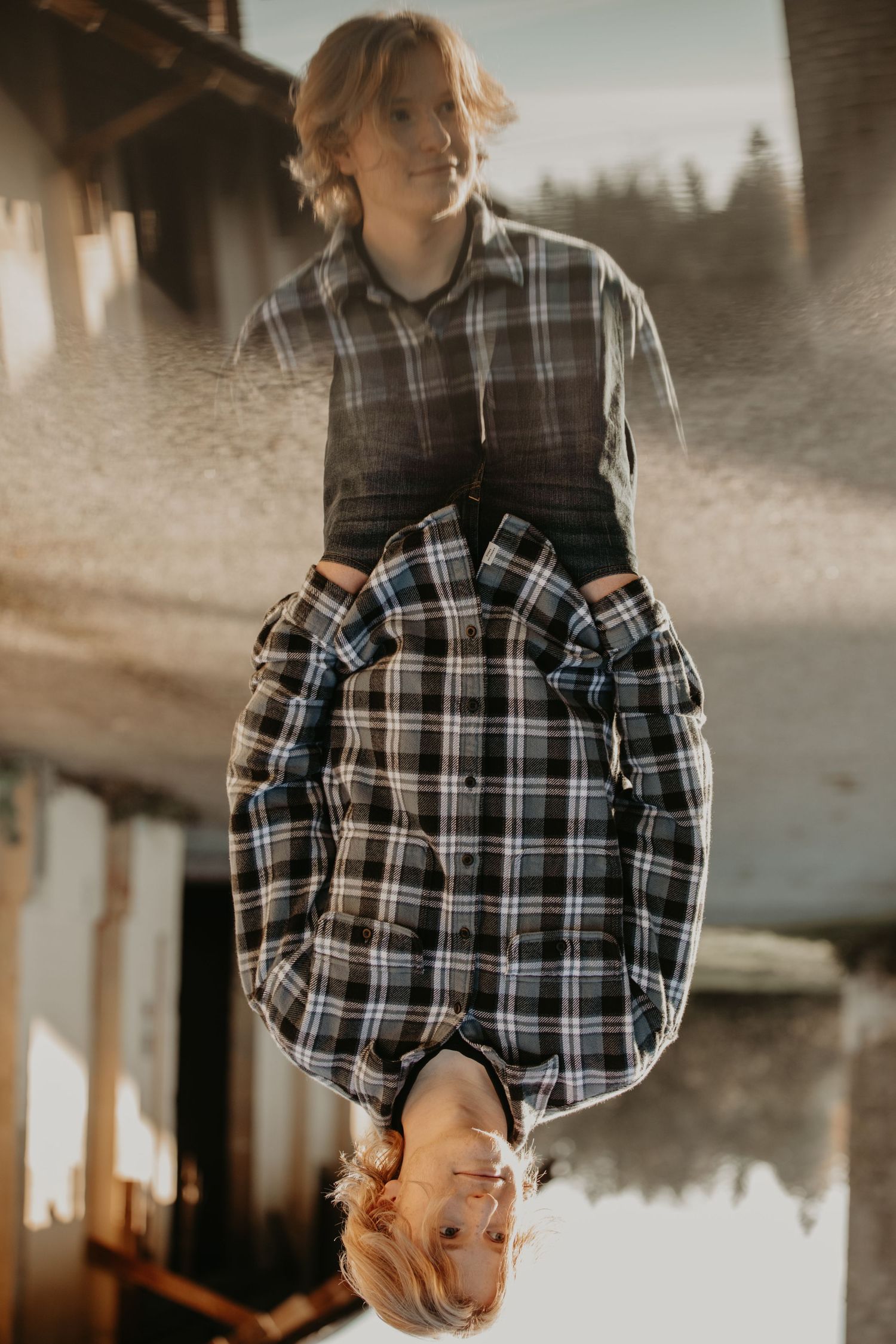 Creative mirrored portrait of someone in a plaid flannel shirt against moody forest scenery in sepia tones.