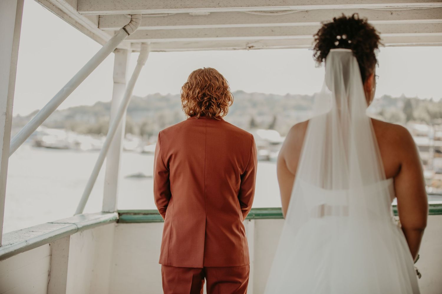 Wedding couple and guests stand on a boat dock overlooking a marina during a waterfront celebration.