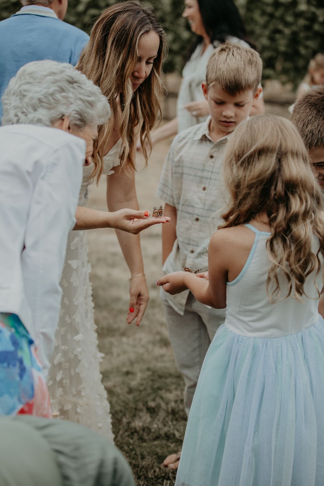 Children in light blue dresses play together at an outdoor celebration.