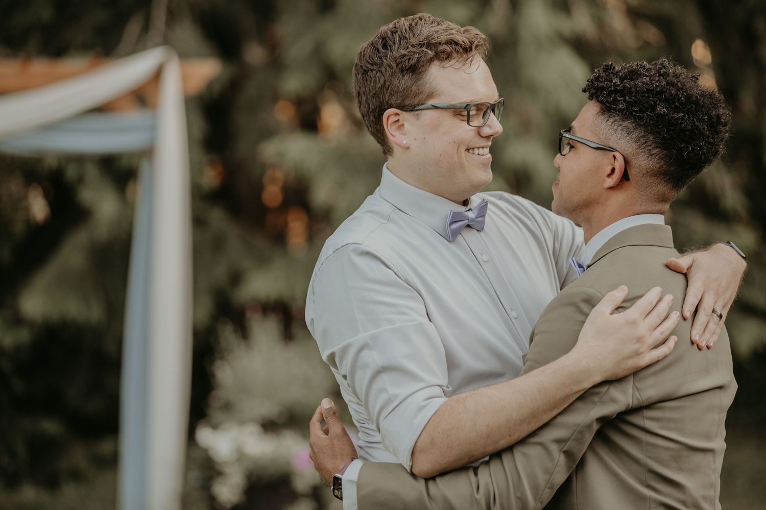 Two men in formal attire sharing an emotional embrace during what appears to be a wedding ceremony.